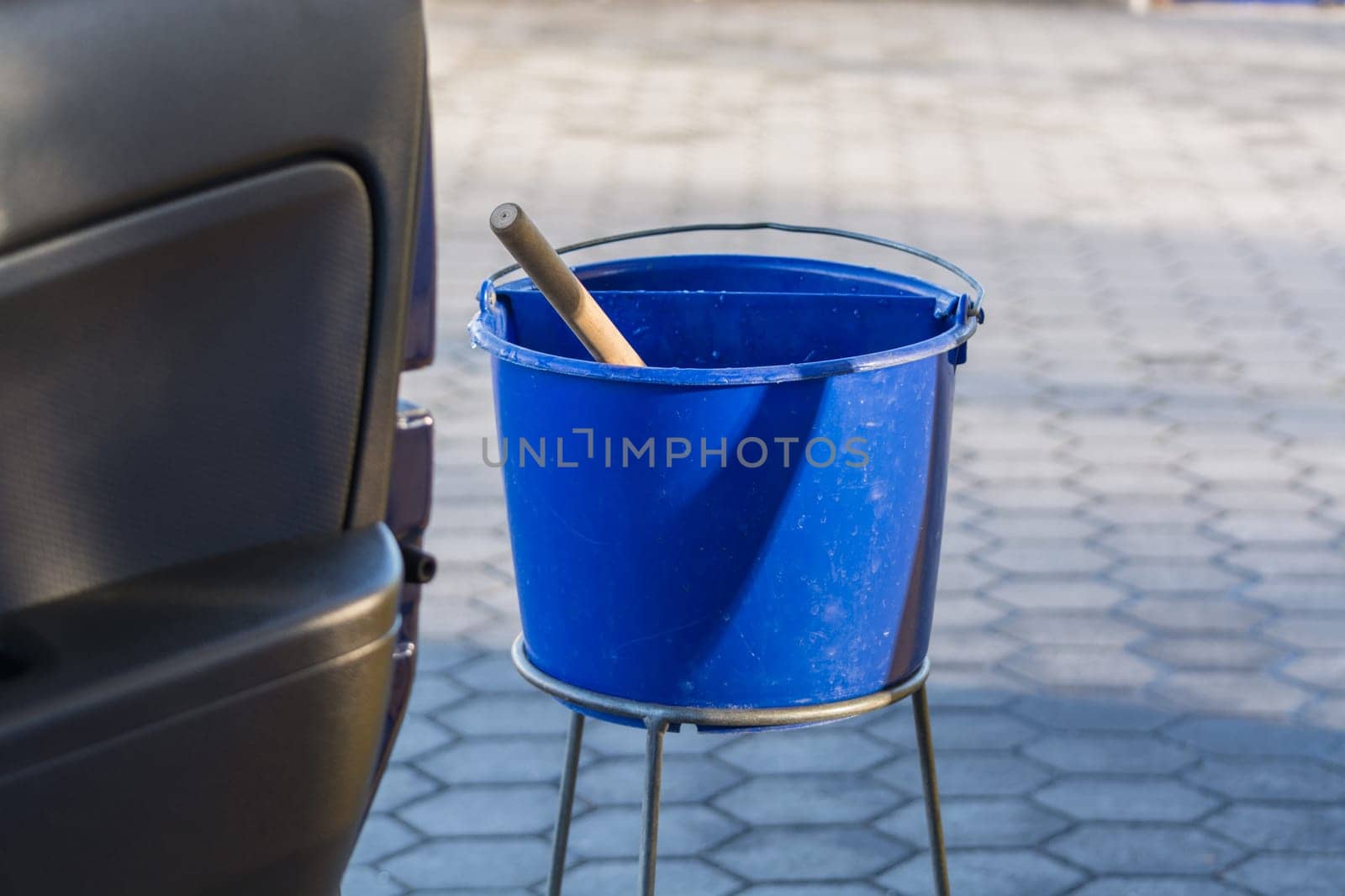 Blue bucket with water at a gas station to clean the windshield.
