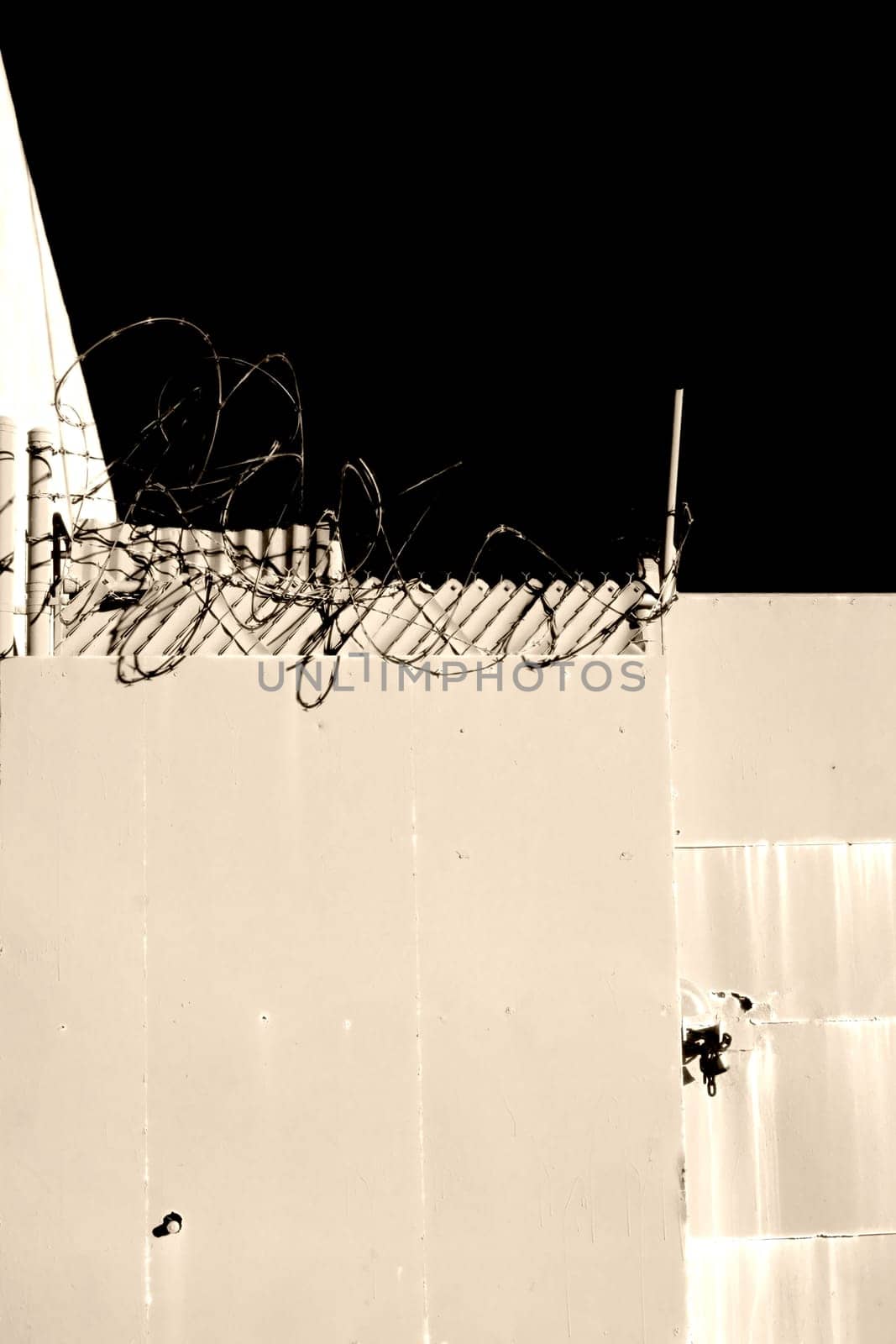 Barbed wire with razor-sharp blades on the fence of a property.