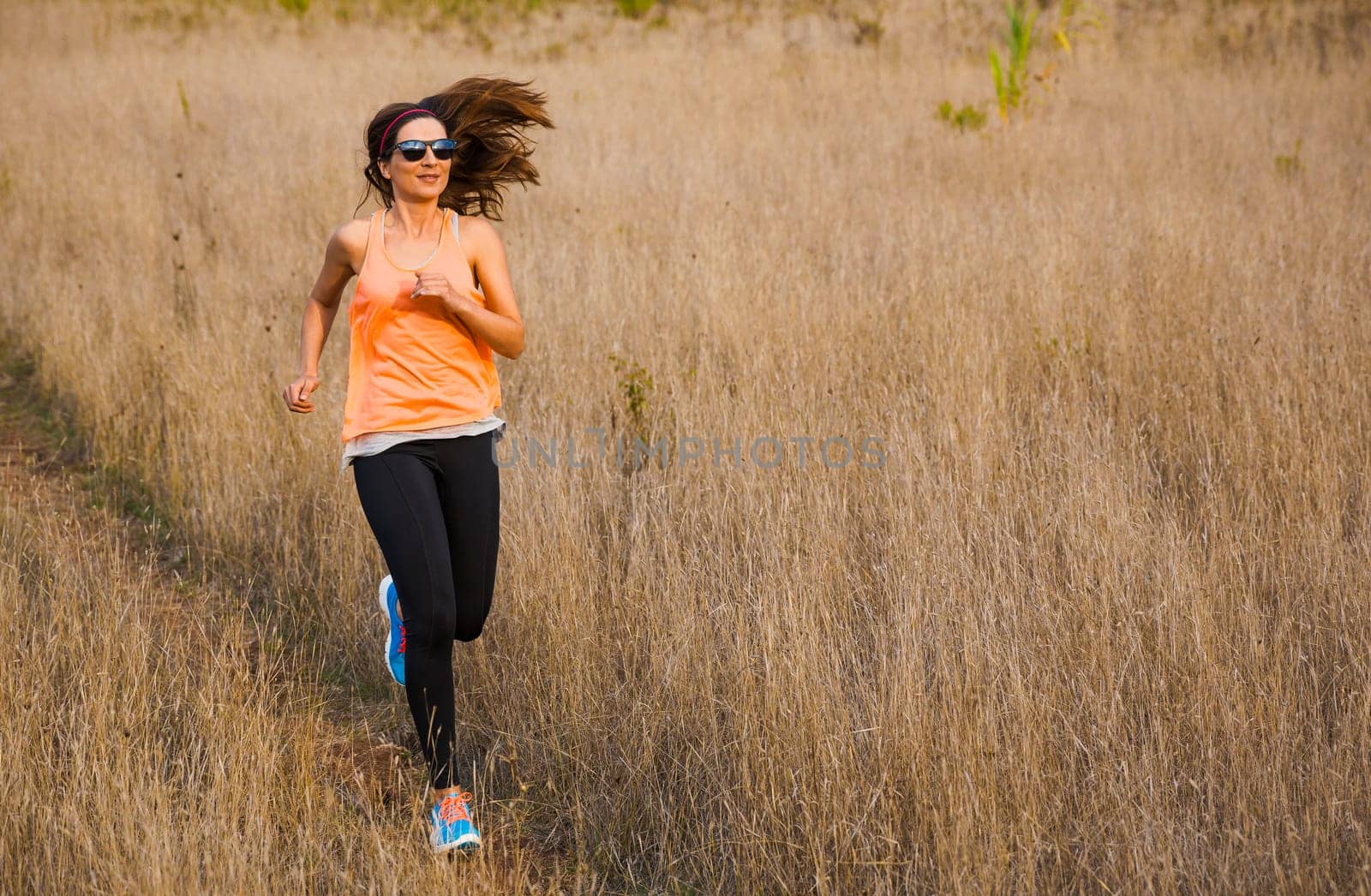 Shot of an attractive woman running outdoor on a meadow