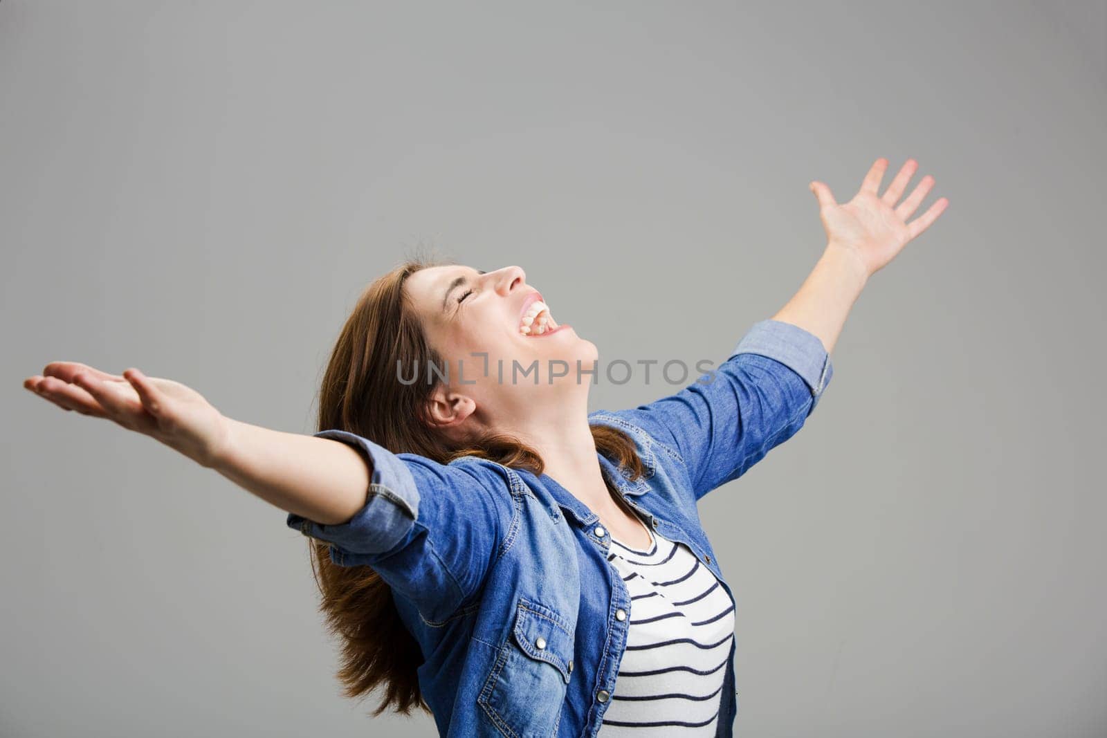 Studio portrait of a happy woman with arms raised