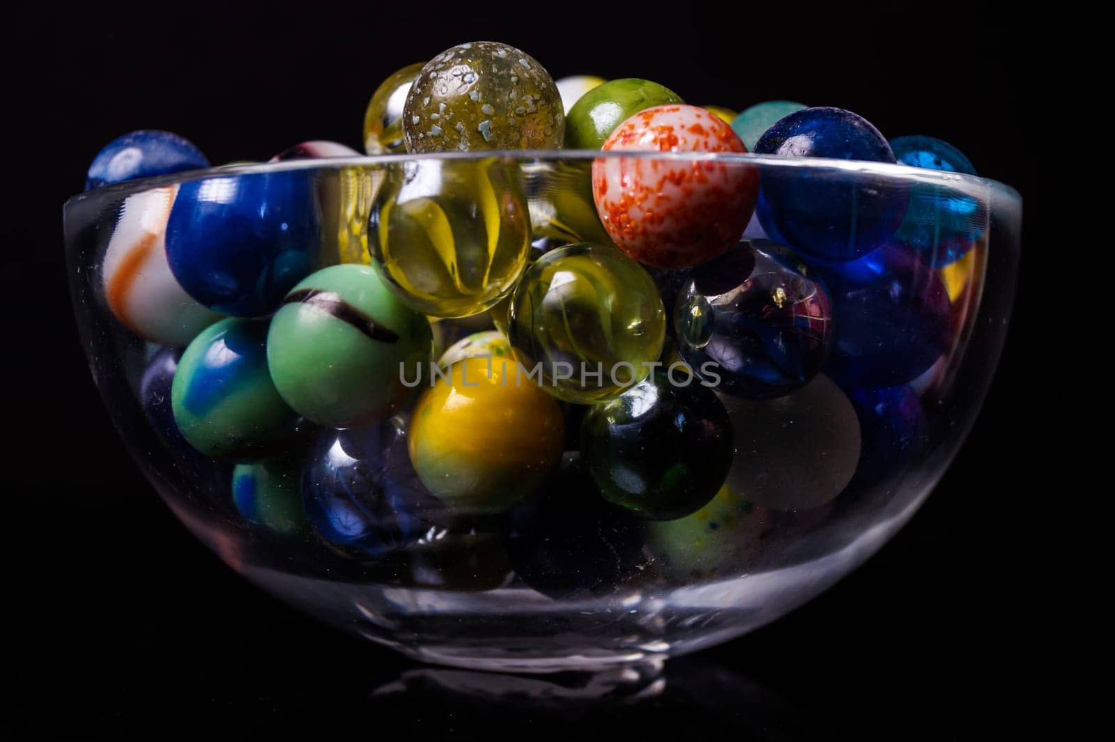 Colorful marbles in a bowl, isolated on black