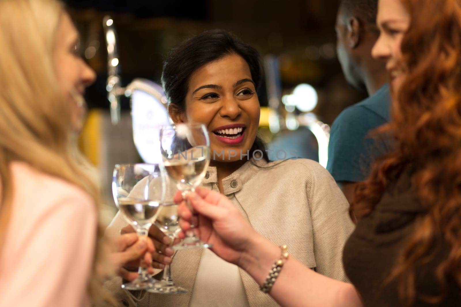 Three women toasting their glasses in a bar