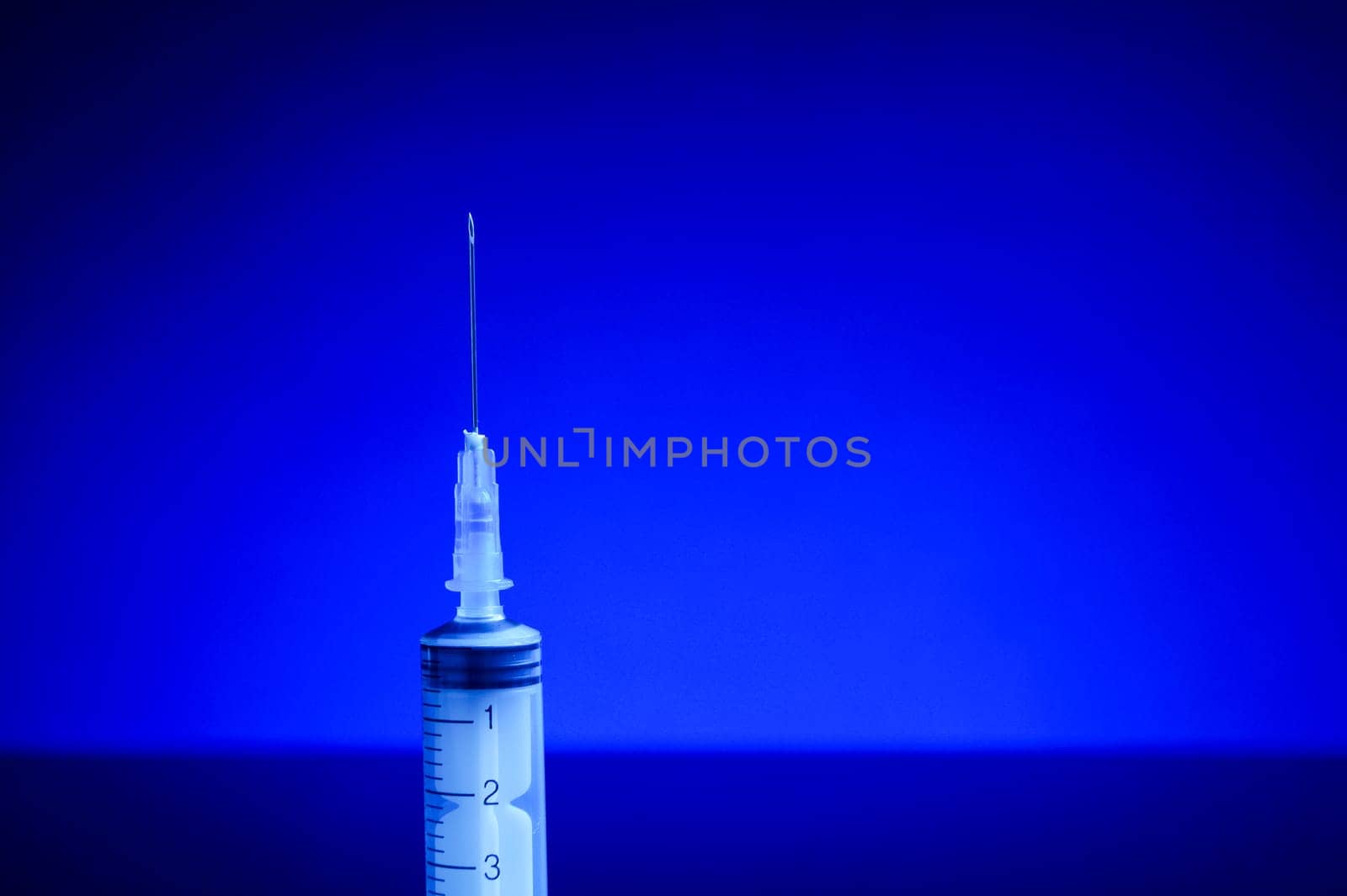 Syringe with needle, upright standing, isolated with background light