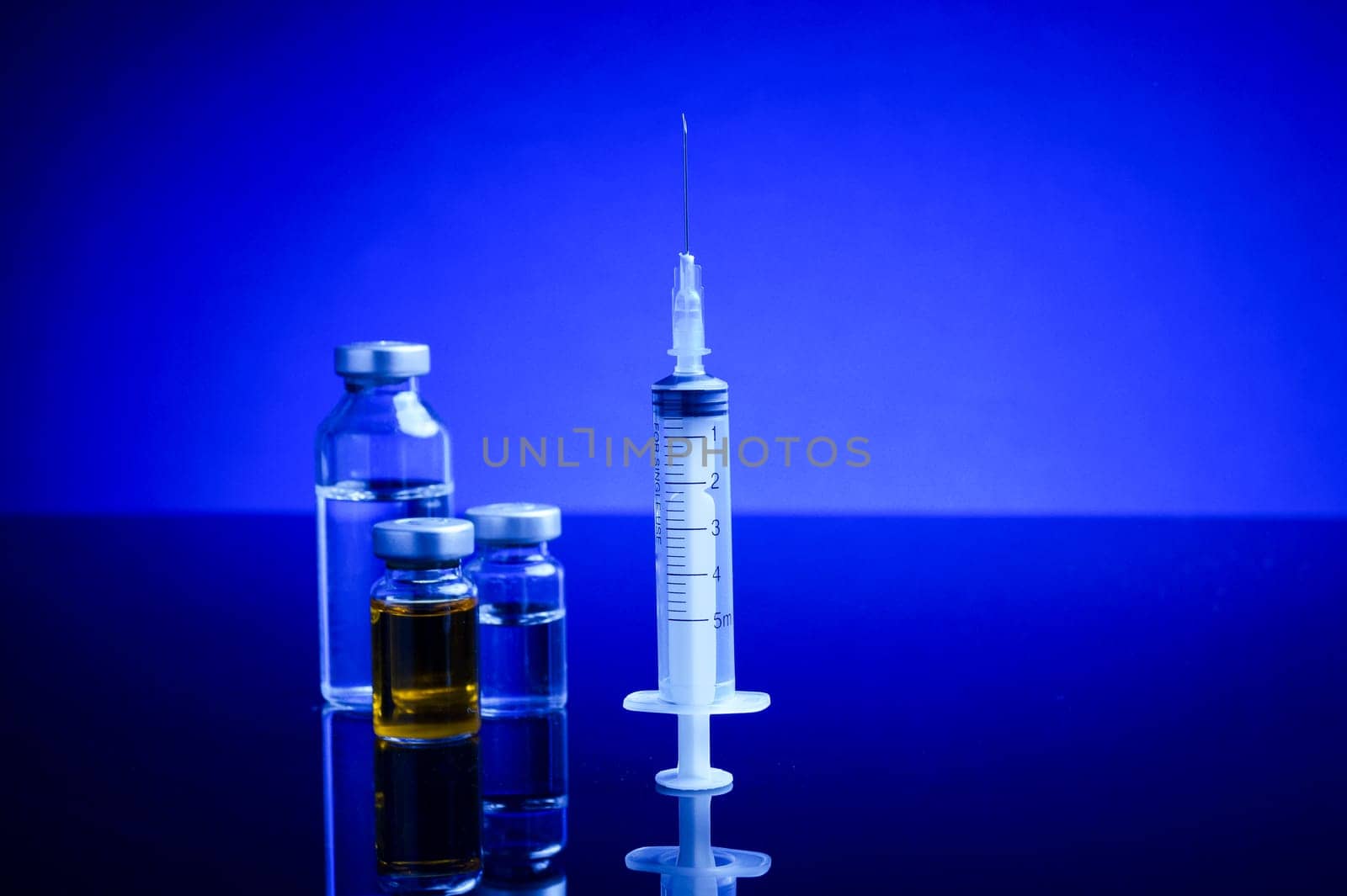 Syringe and medical vials, upright standing, isolated with background light
