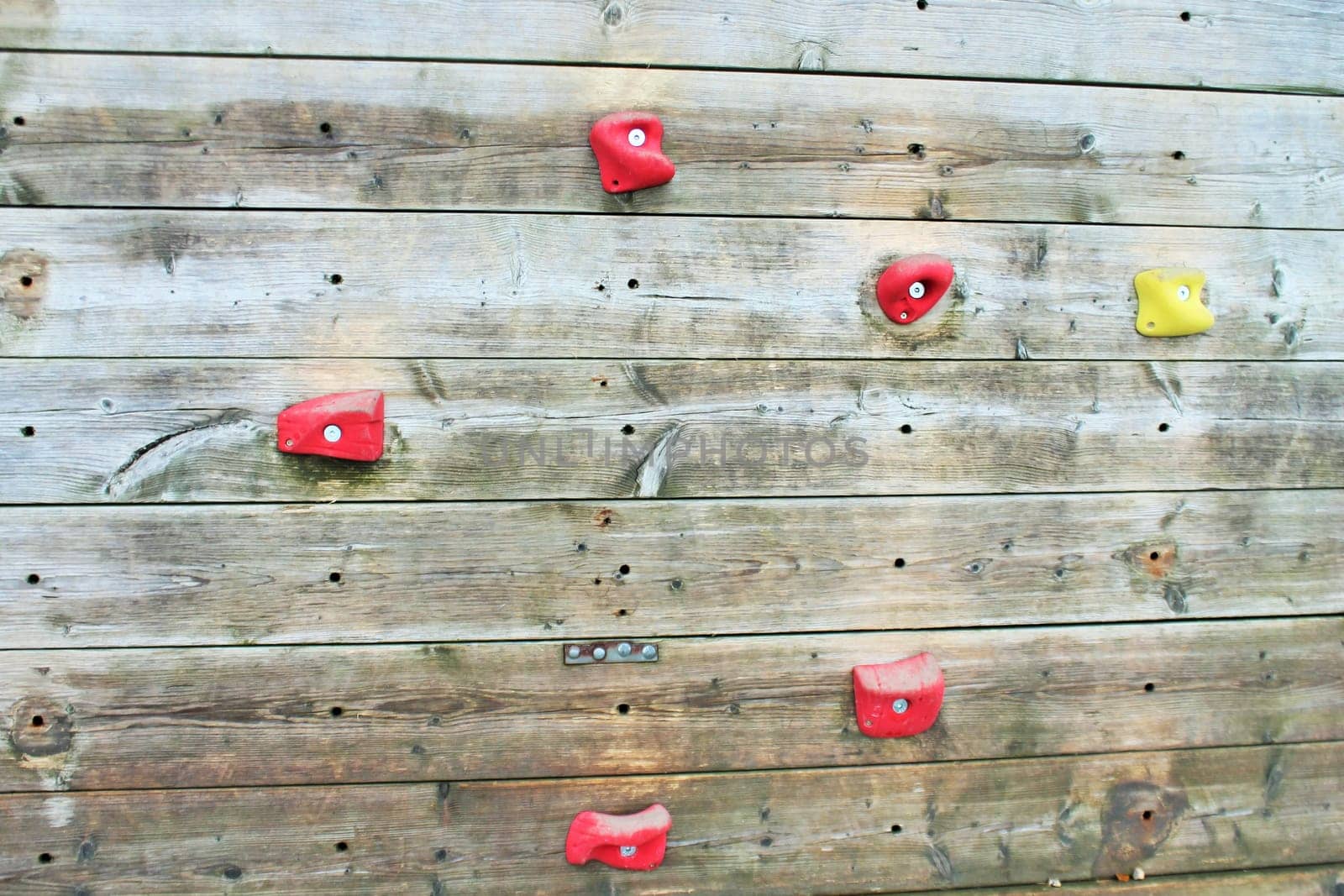 wooden climbing wall with bright colored foot holds