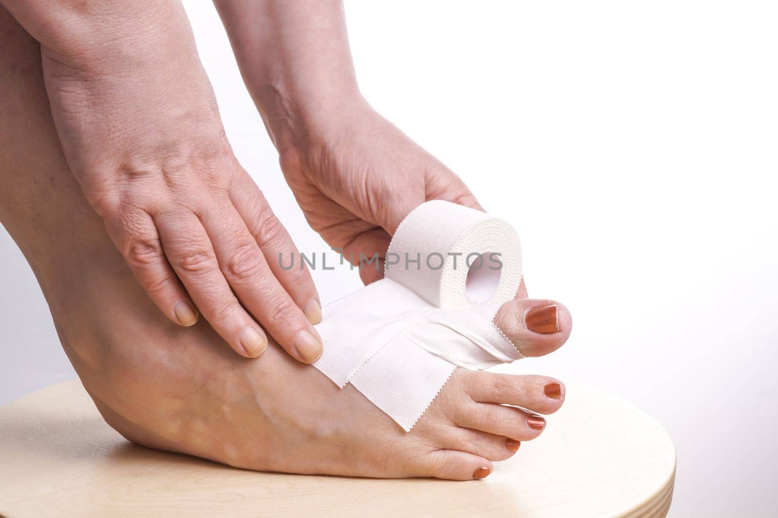 Hands rolling Therapeutic self adhesive tape on a Foot with a sports injury