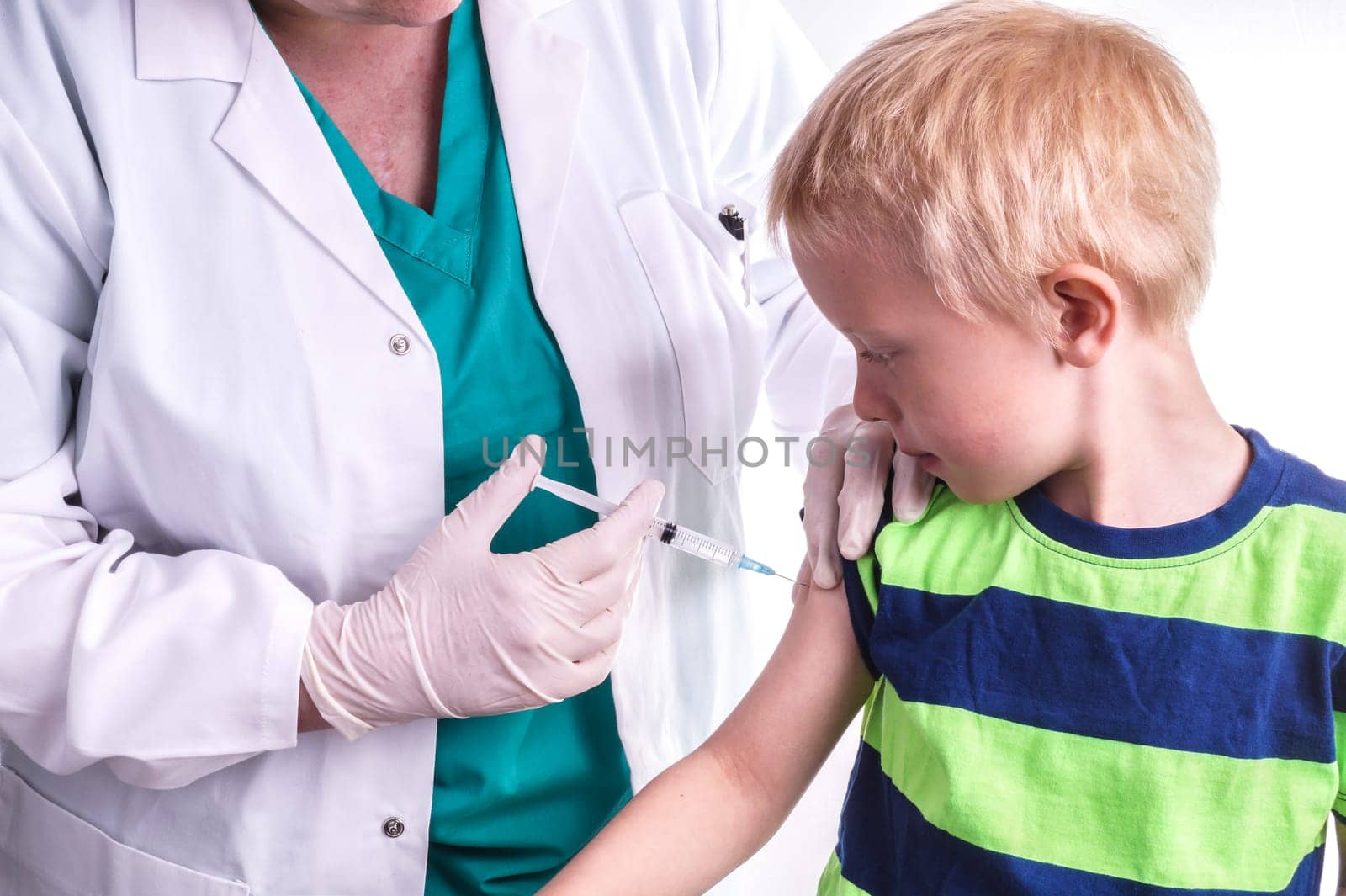 little boy given an injection by the family doctor. The female doctor gives the child an injection in the upper arm. It can be both a vaccination or as part of the boy's medical treatment