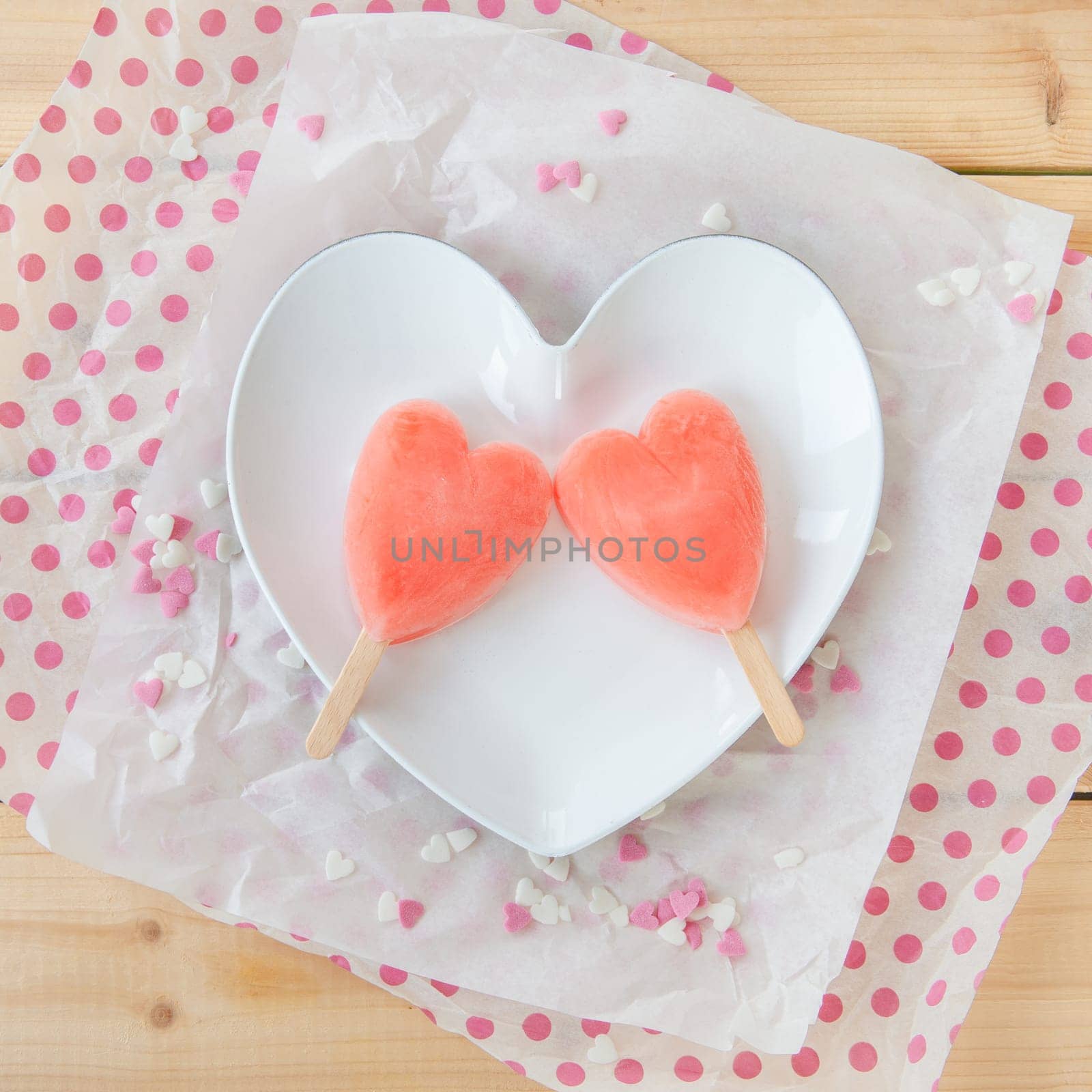 Ice cream on the stem in heart shape with colorful sugar hearts