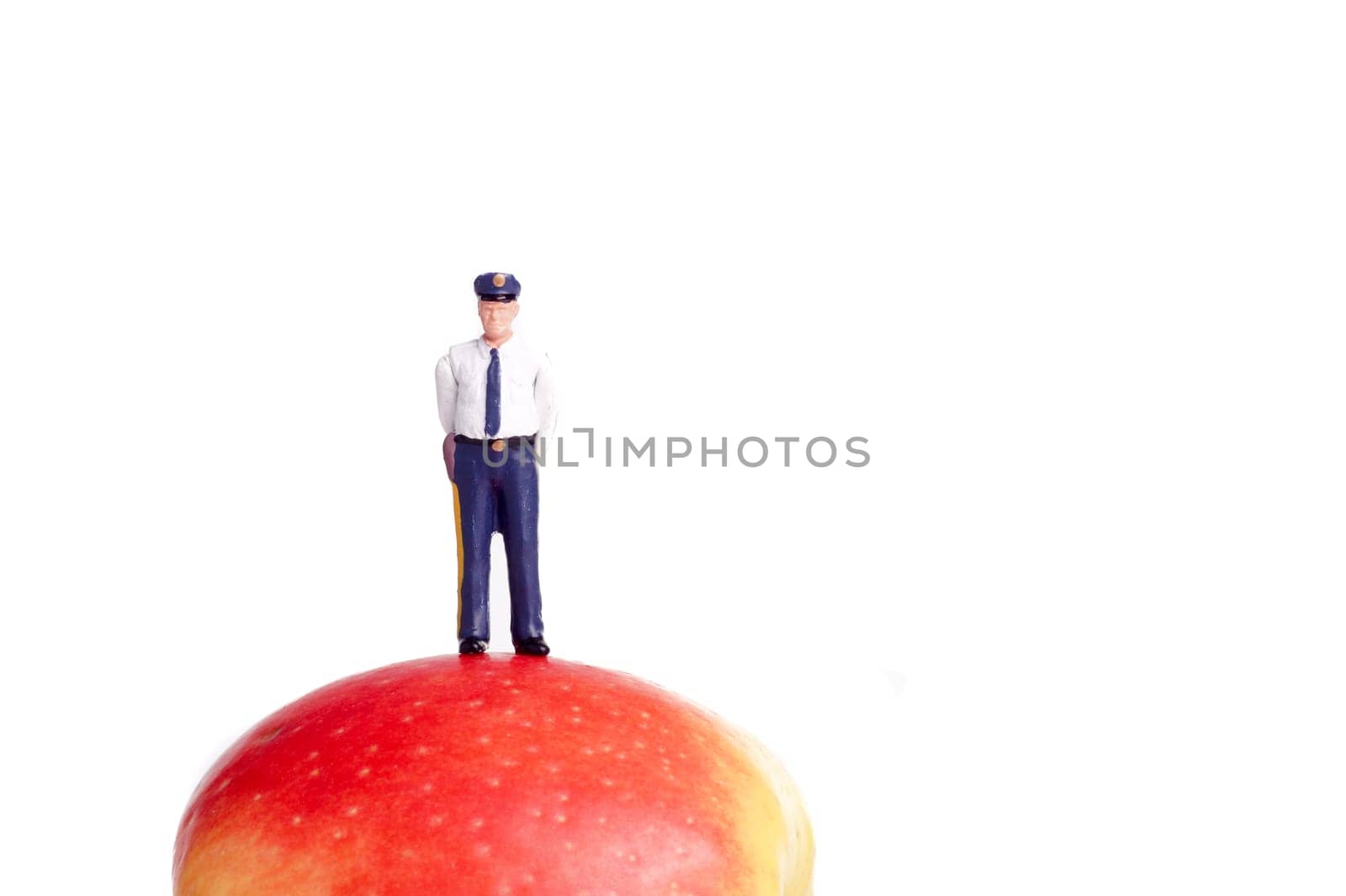 small figure of a Policeman standing on an Apple, isolated on white