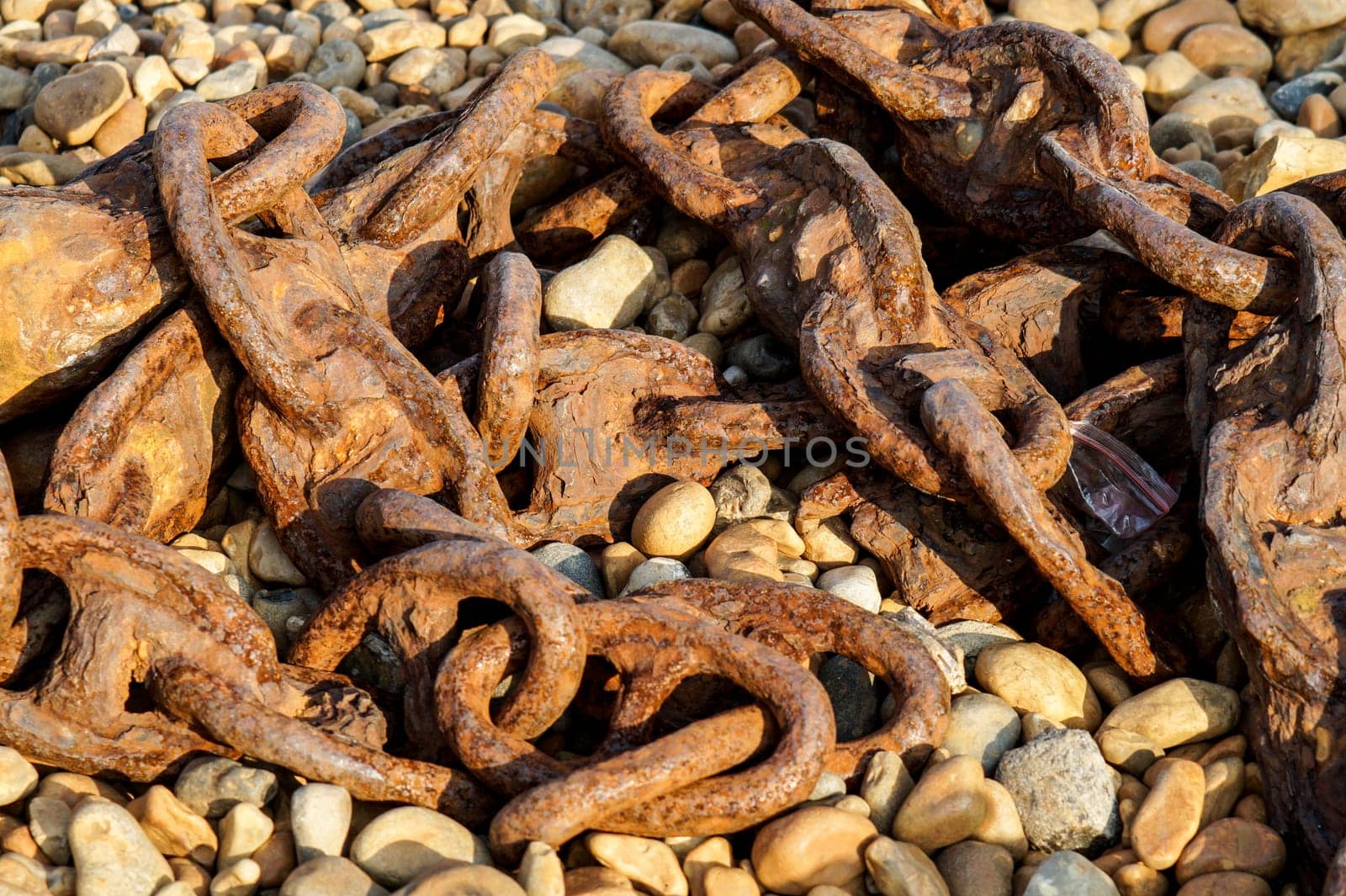 Old rusty ship chain lying on a rocky beach