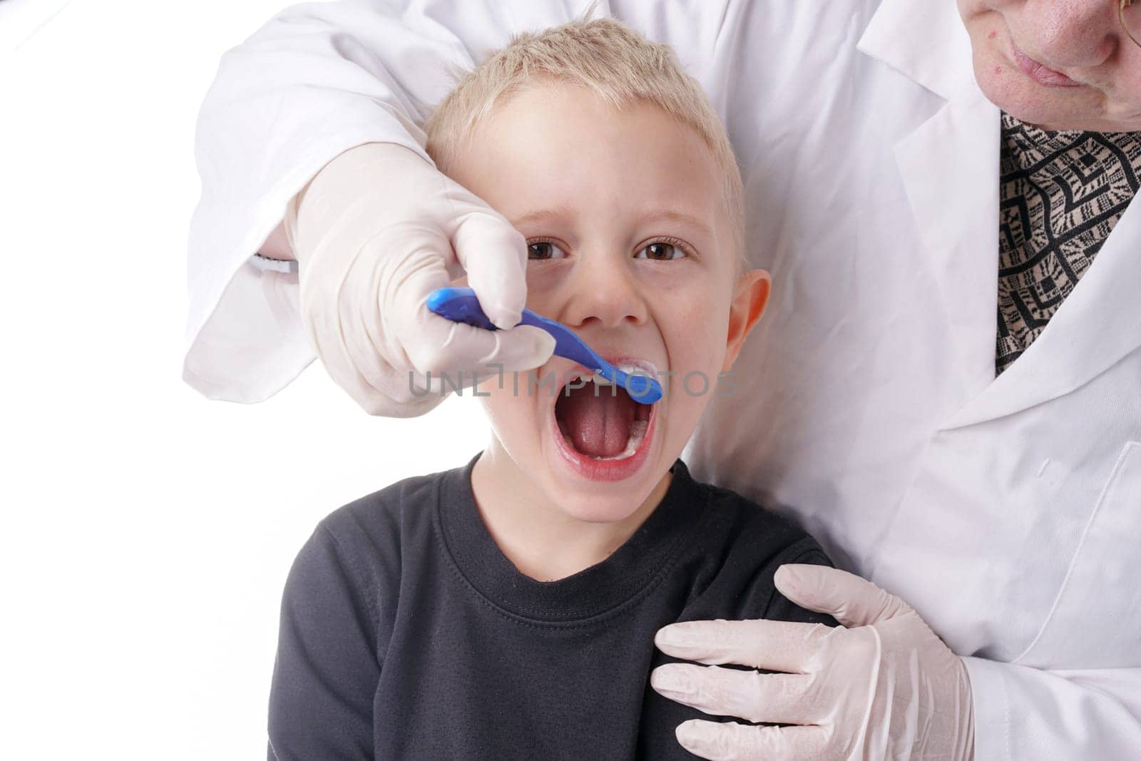 Young Boy gets help by the Dentist to brush his teeth, Isolated on white