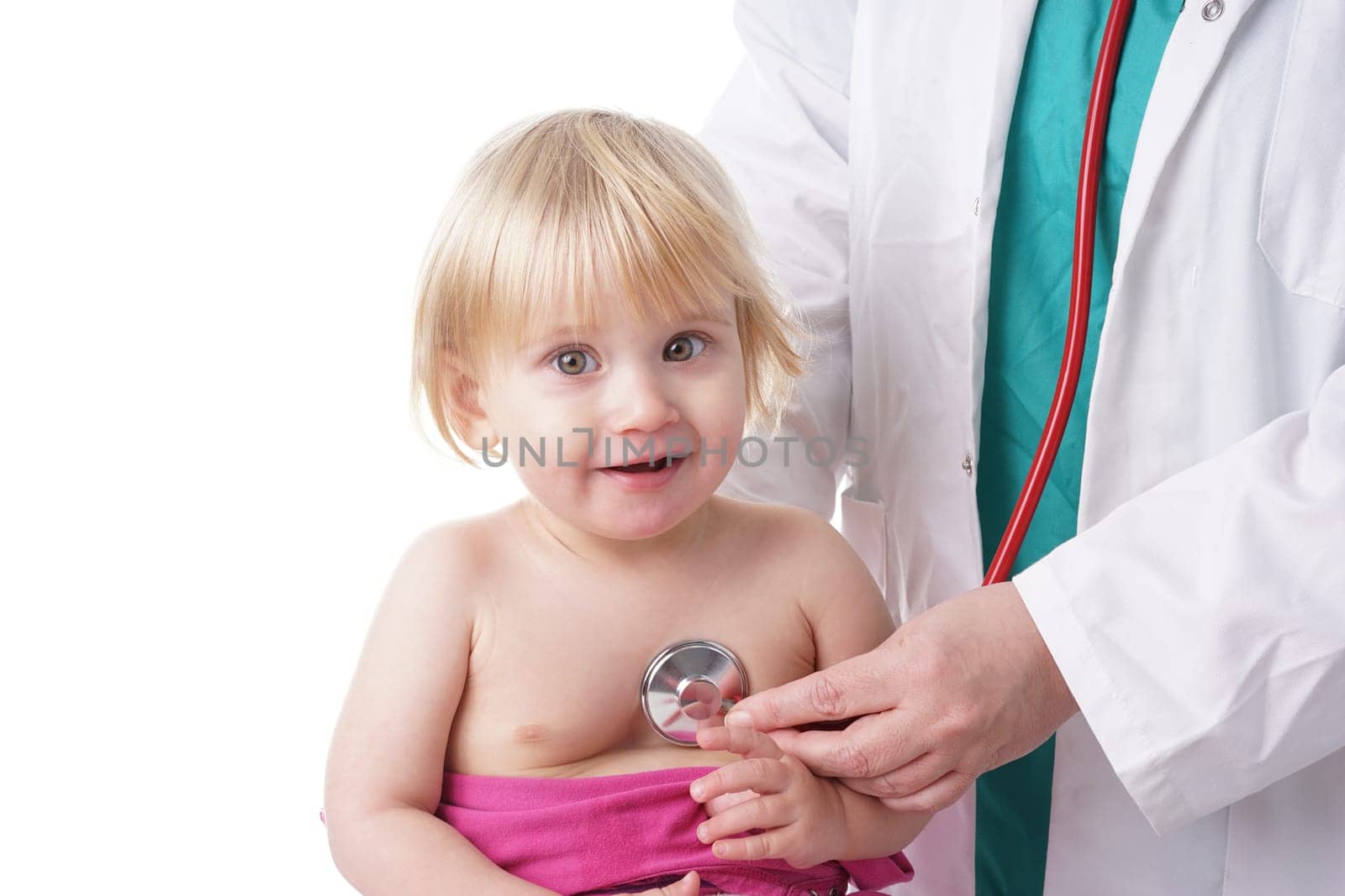 The doctor examines toddler child and listening to heart and lungs with stethoscope. The baby girl is happy, isolated on white