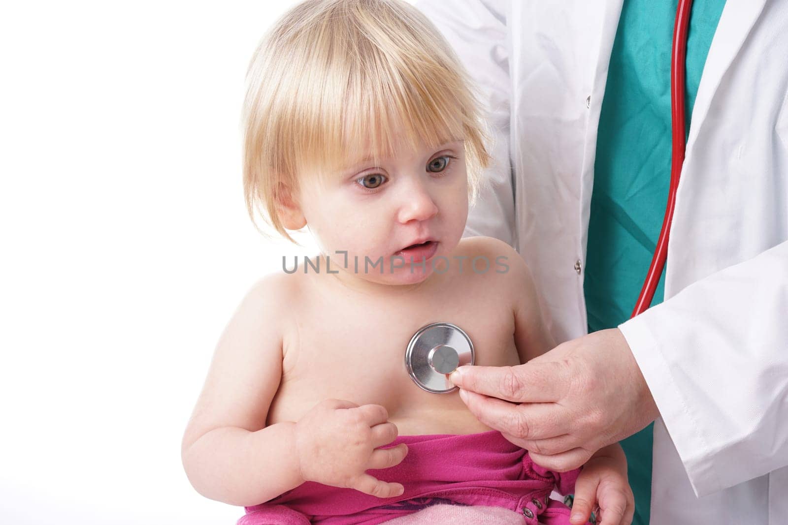 The doctor examines toddler child and listening to heart and lungs with stethoscope. The baby girl is happy, isolated on white