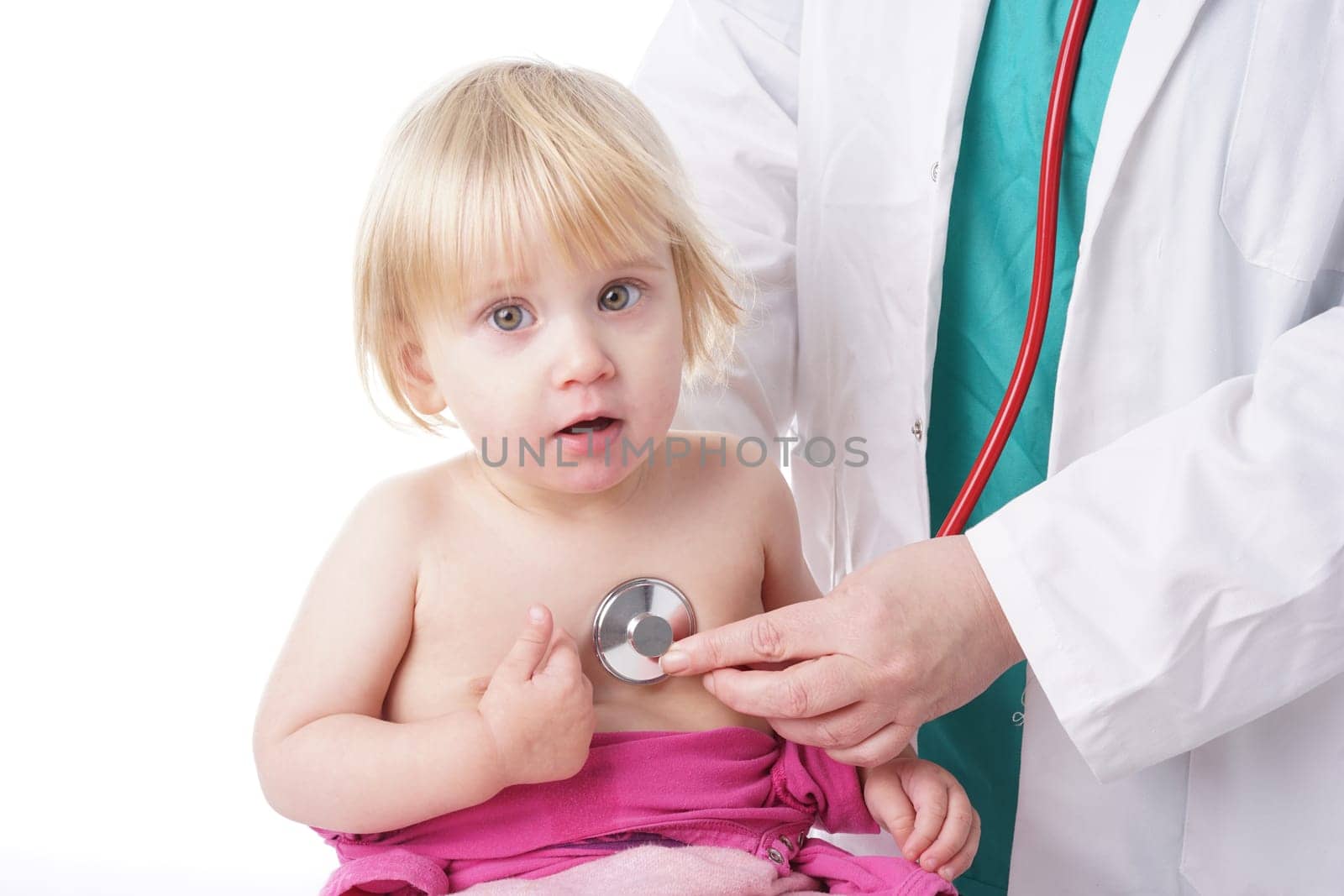 The doctor examines toddler child and listening to heart and lungs with stethoscope. The baby girl is happy, isolated on white