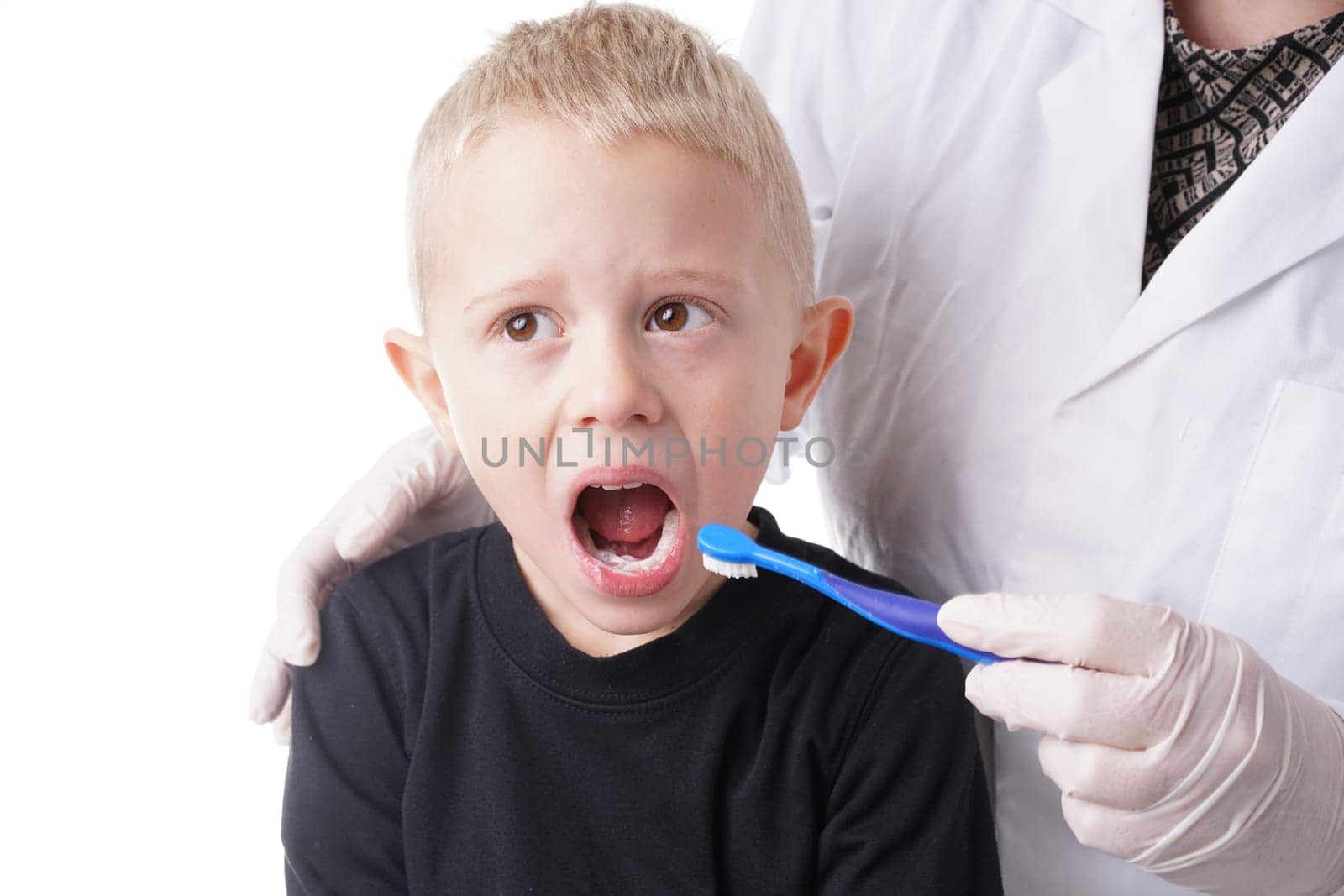 Young Boy gets help by the Dentist to brush his teeth, Isolated on white