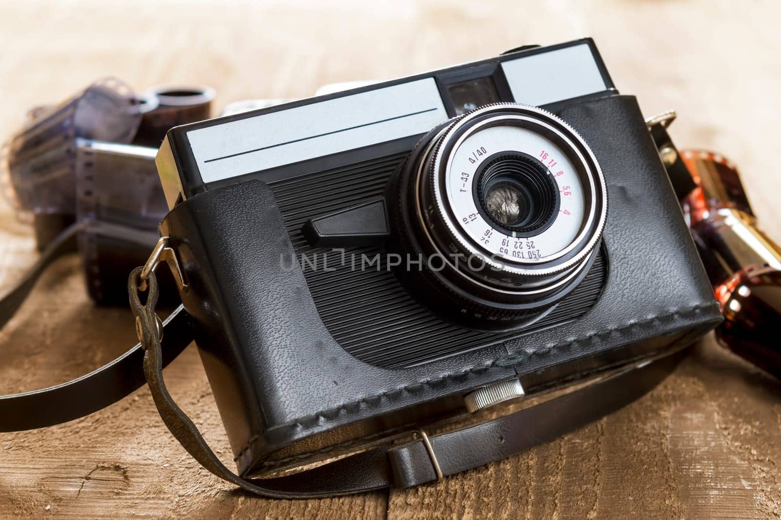 old camera and blank film strip on wooden table