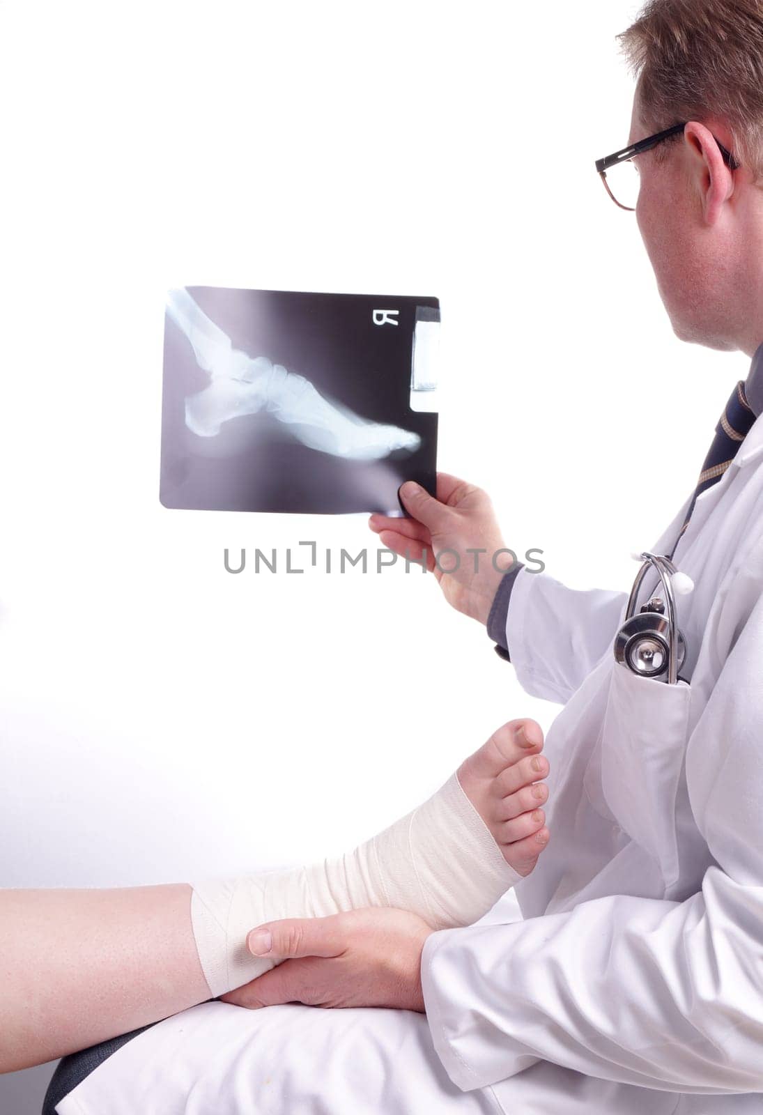 The doctor examines an X-ray picture , while the patient&#39 s sprained foot resting in his hand