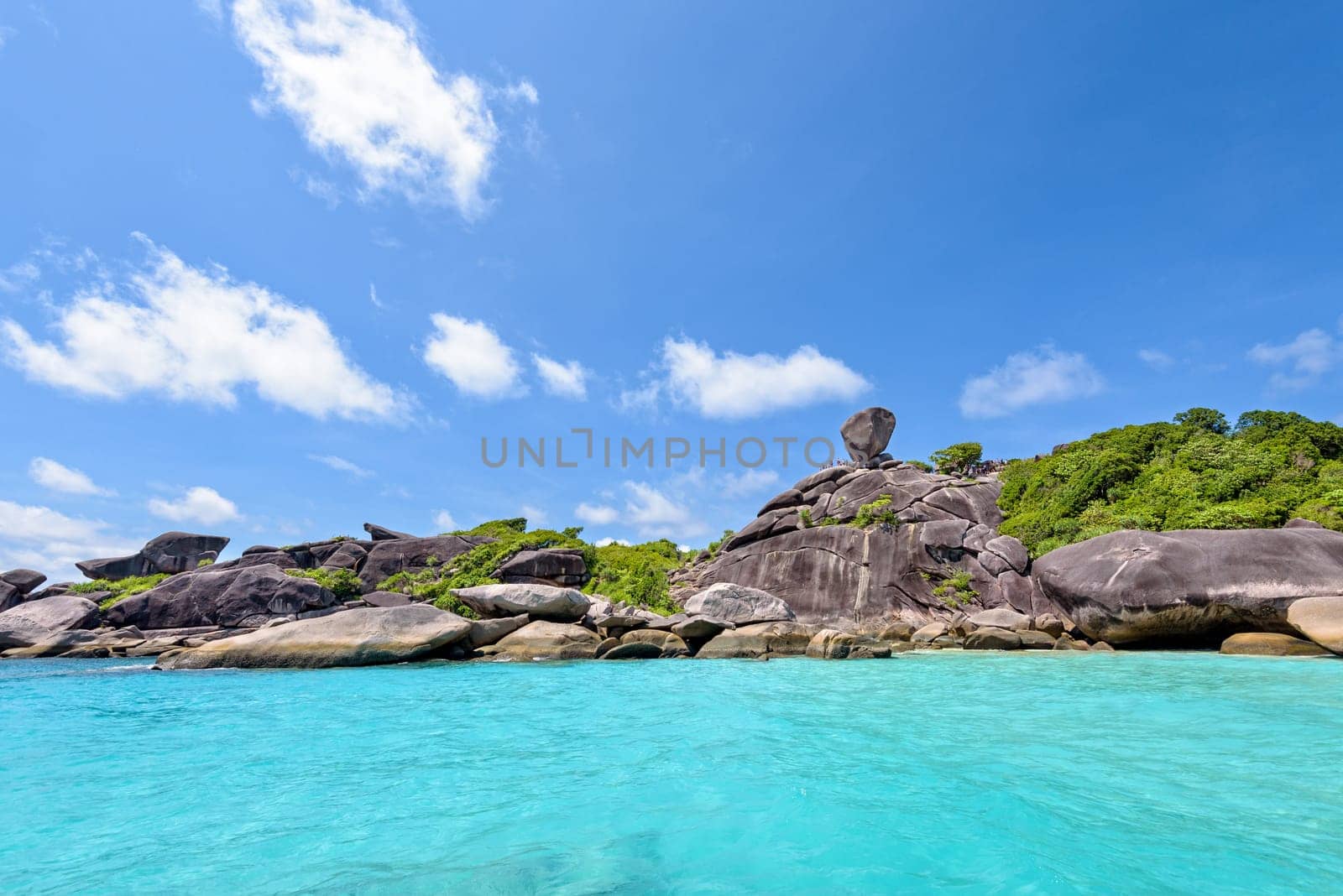 Beautiful landscape rock is a symbol of Similan Islands and people over the blue sea under summer sky in Mu Ko Similan National Park, Phang Nga province, Thailand