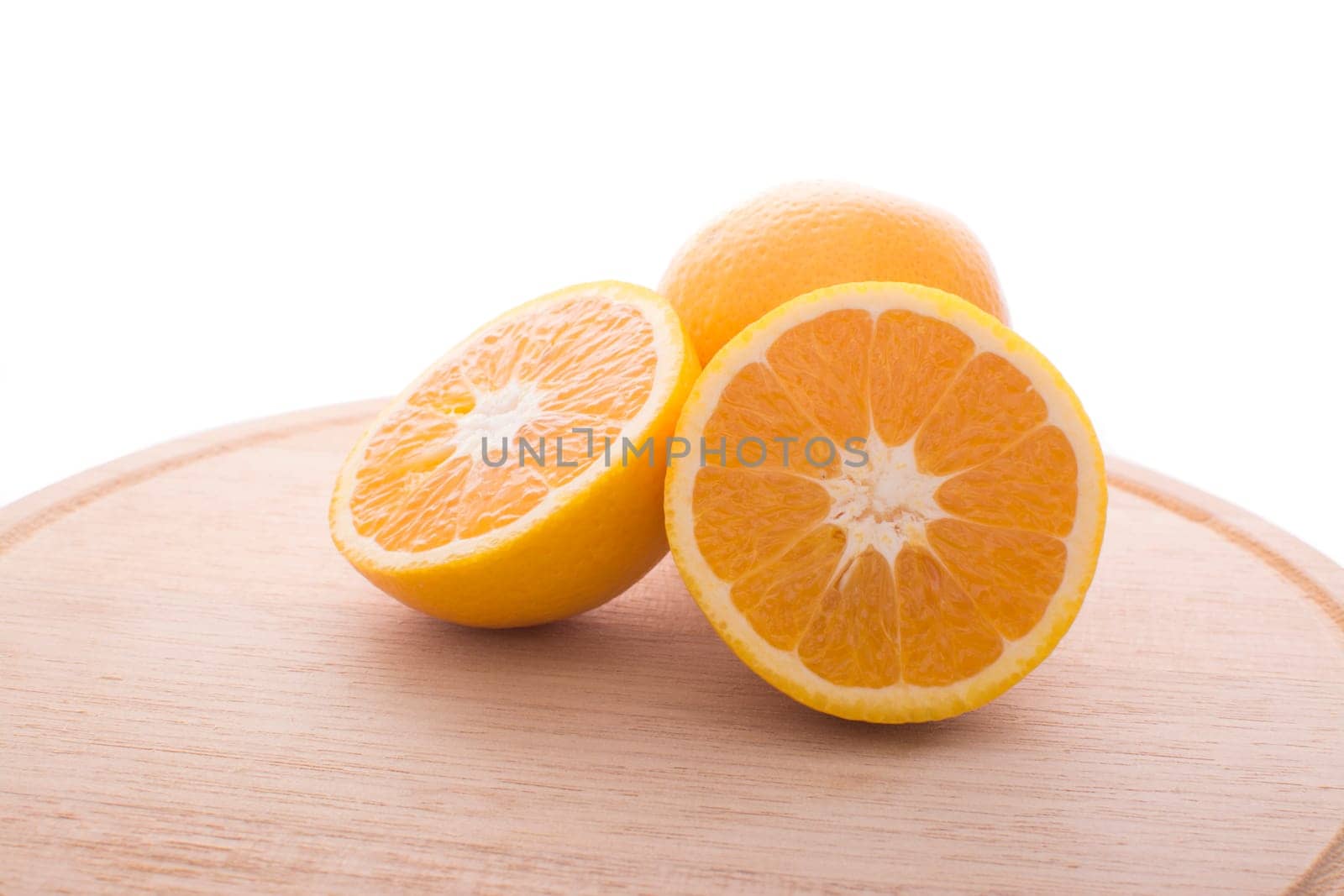 Approach and presentation of an orange split in half and a full in the back. They are on a wooden plate and white background