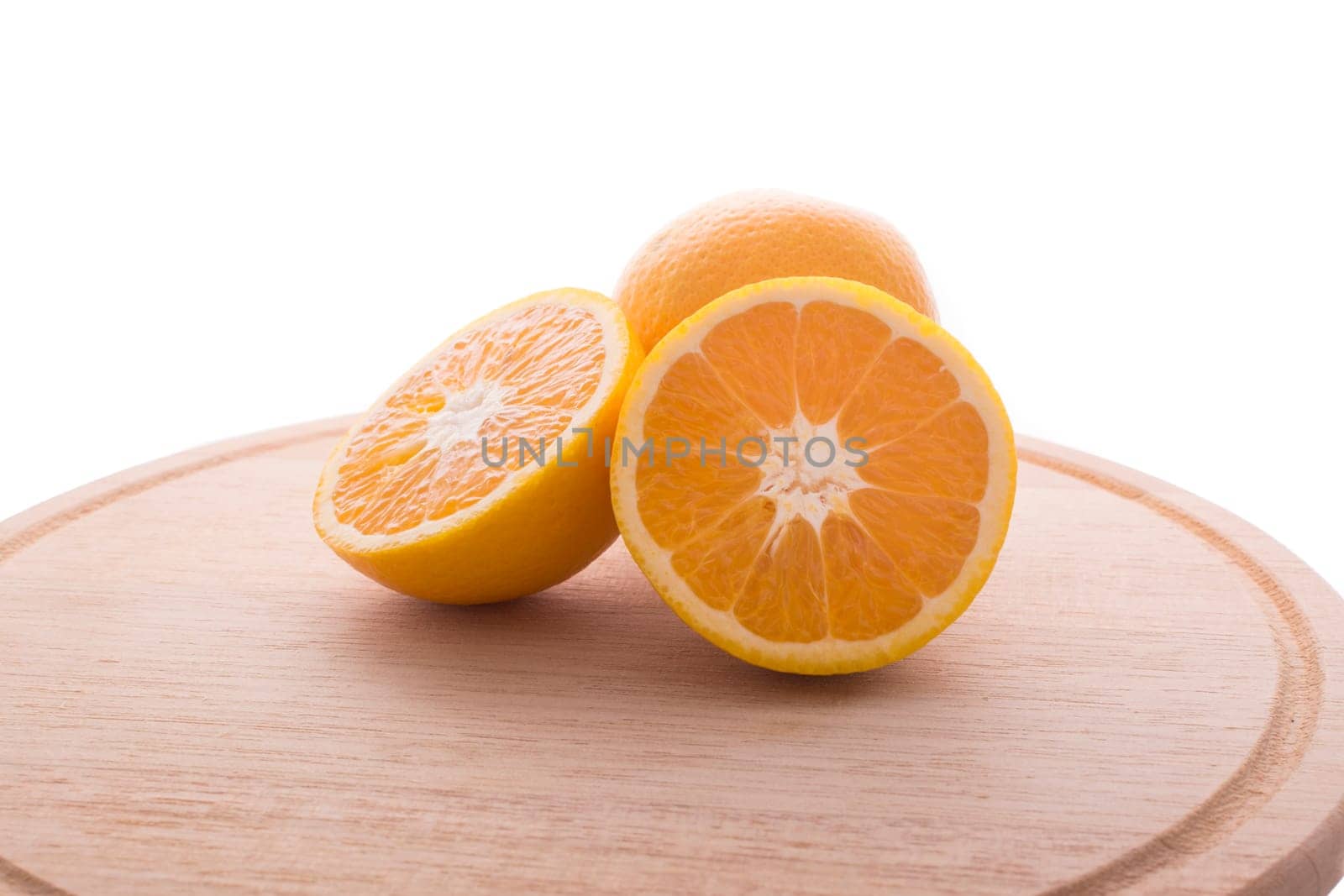 Approach and presentation of an orange split in half and a full in the back. They are on a wooden plate and white background