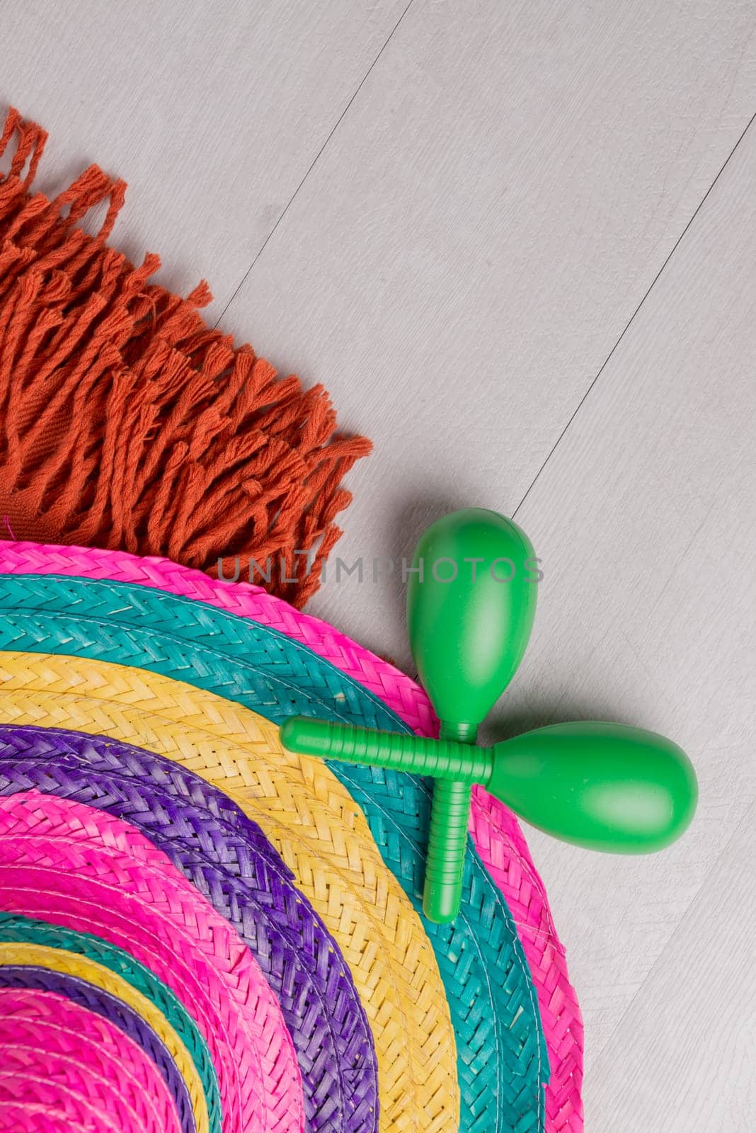 Mexican sombrero, blanket and pair of maracas on wood background.