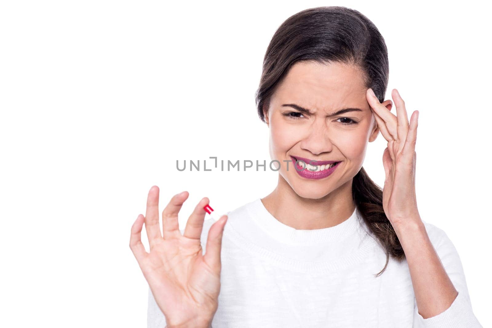 Young woman showing a pill with severe head pain