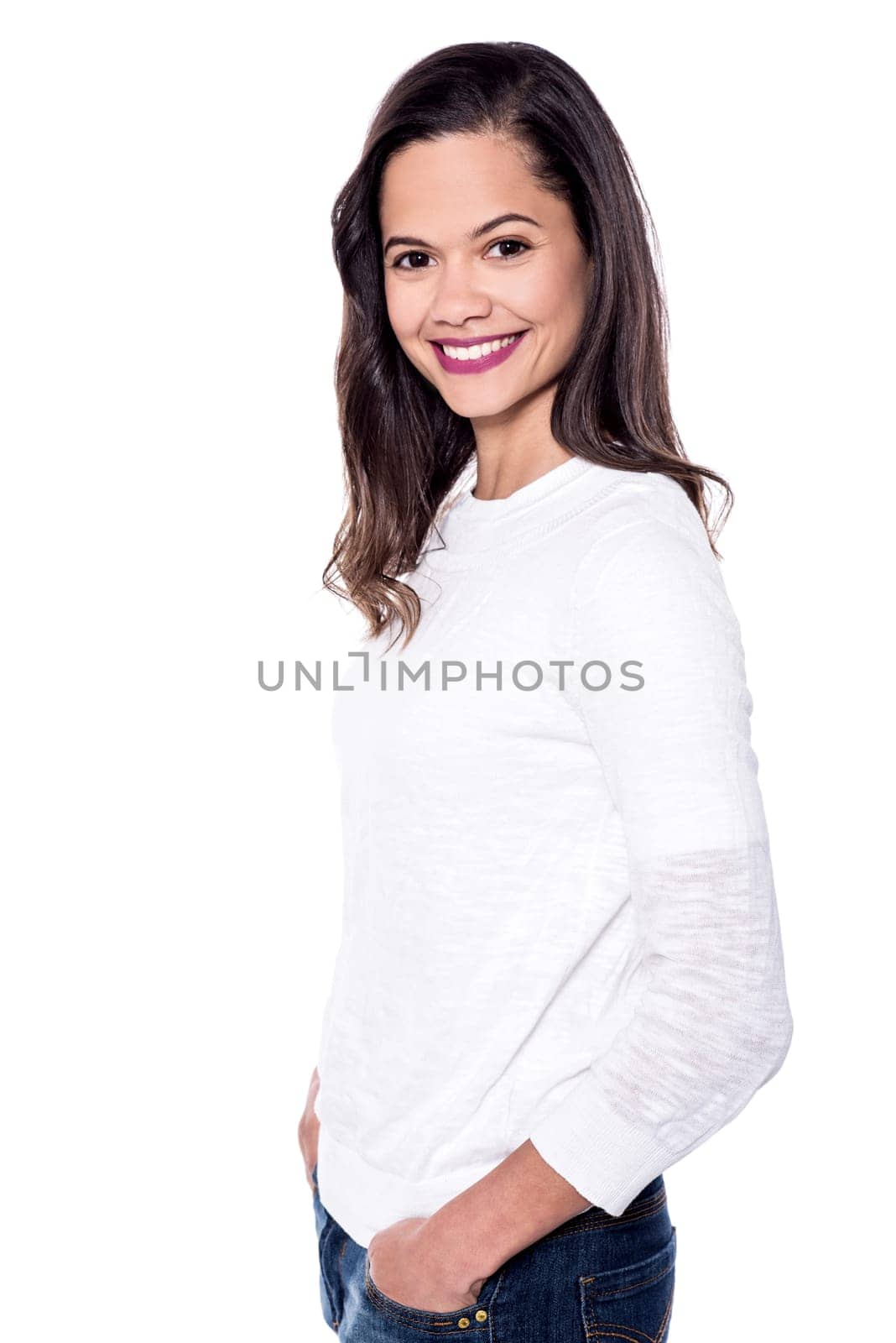 Side pose of smiling young woman with hands in pockets