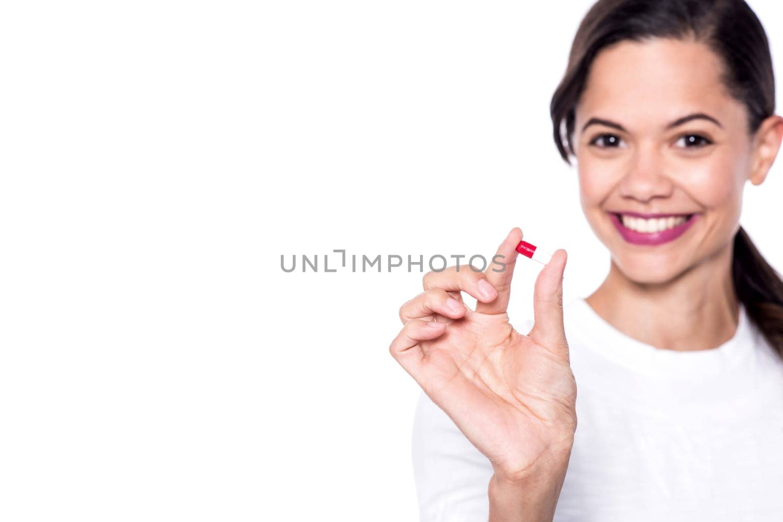 Smiling woman showing a pill over white