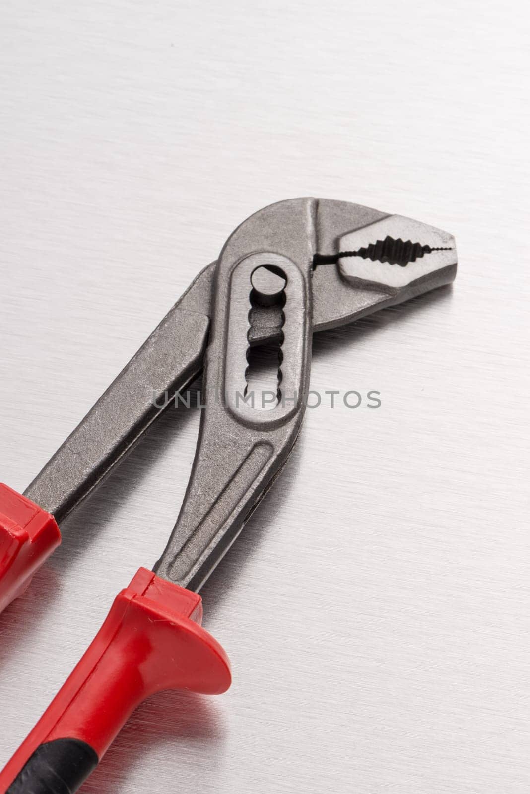 Water pump pliers on metal finish background.