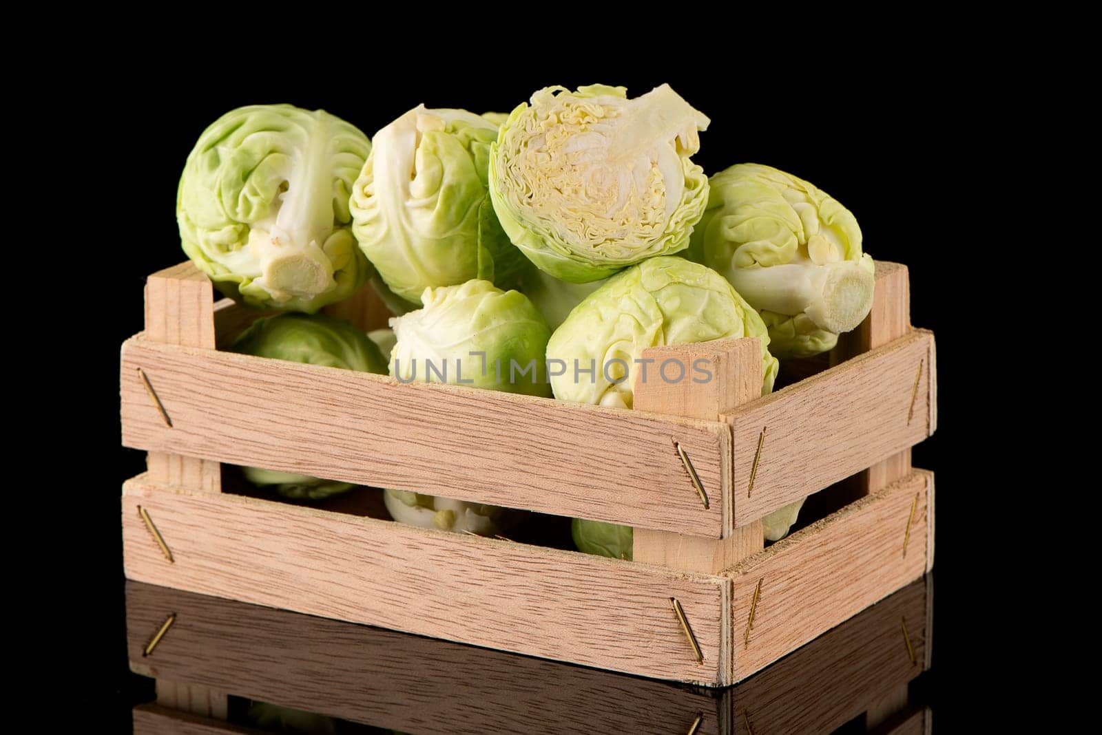 Fresh brussels sprouts on wooden box isolated on black background.