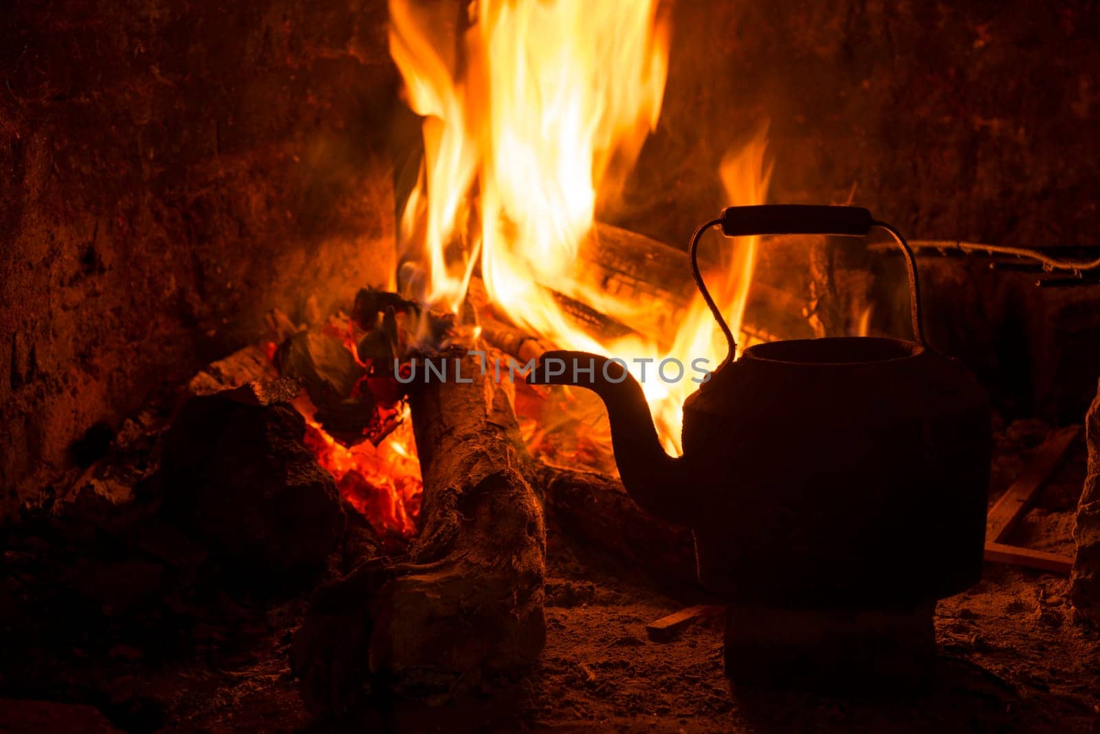 Kettle in fireplace, fire and wood burning. Cozy winter holiday cabin scene.