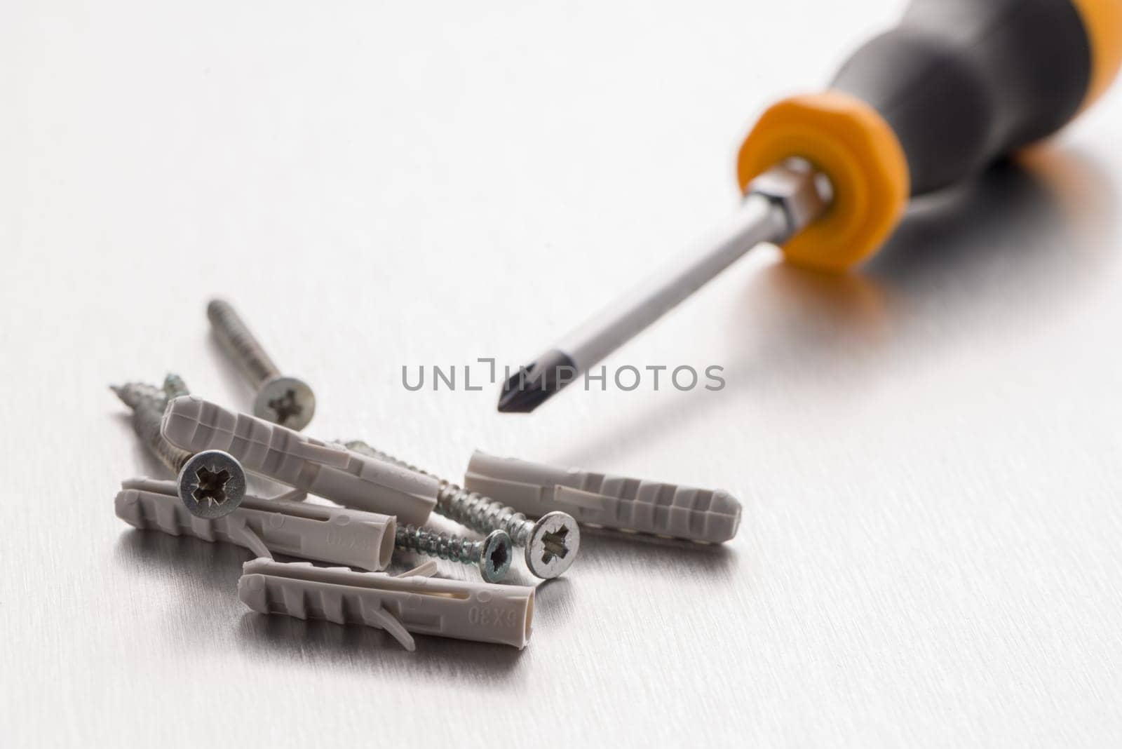 Screwdriver cross bit with screws and plastic dowels.