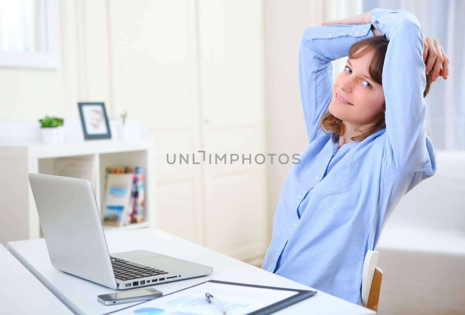 View of a young smiling business woman relaxing at work
