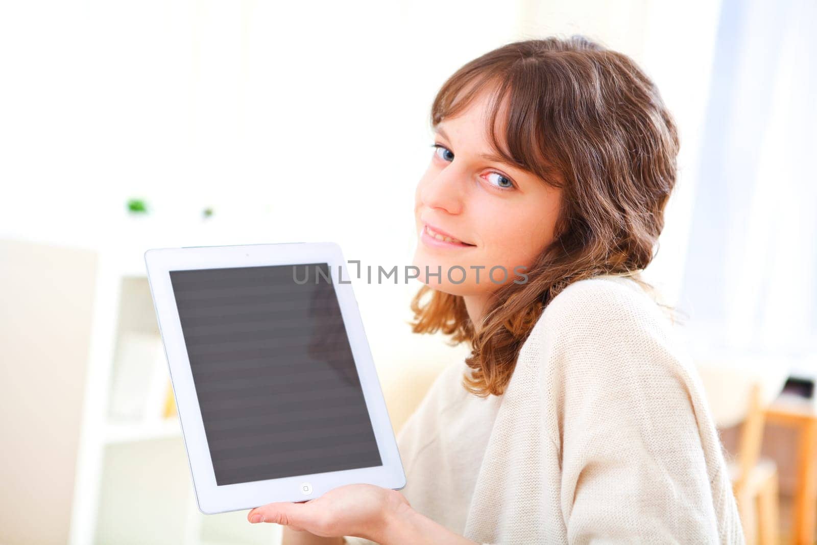 View of a young smiling woman using a tablet on a sofa