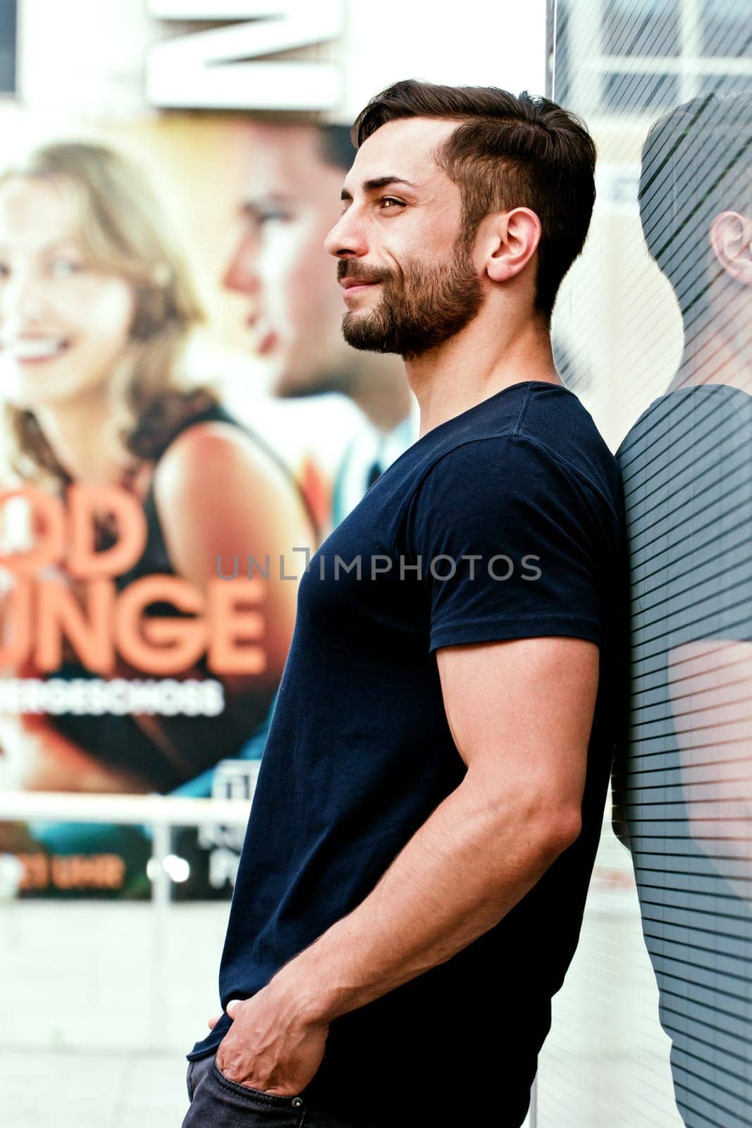 Young man in the city - In the background a promotional poster