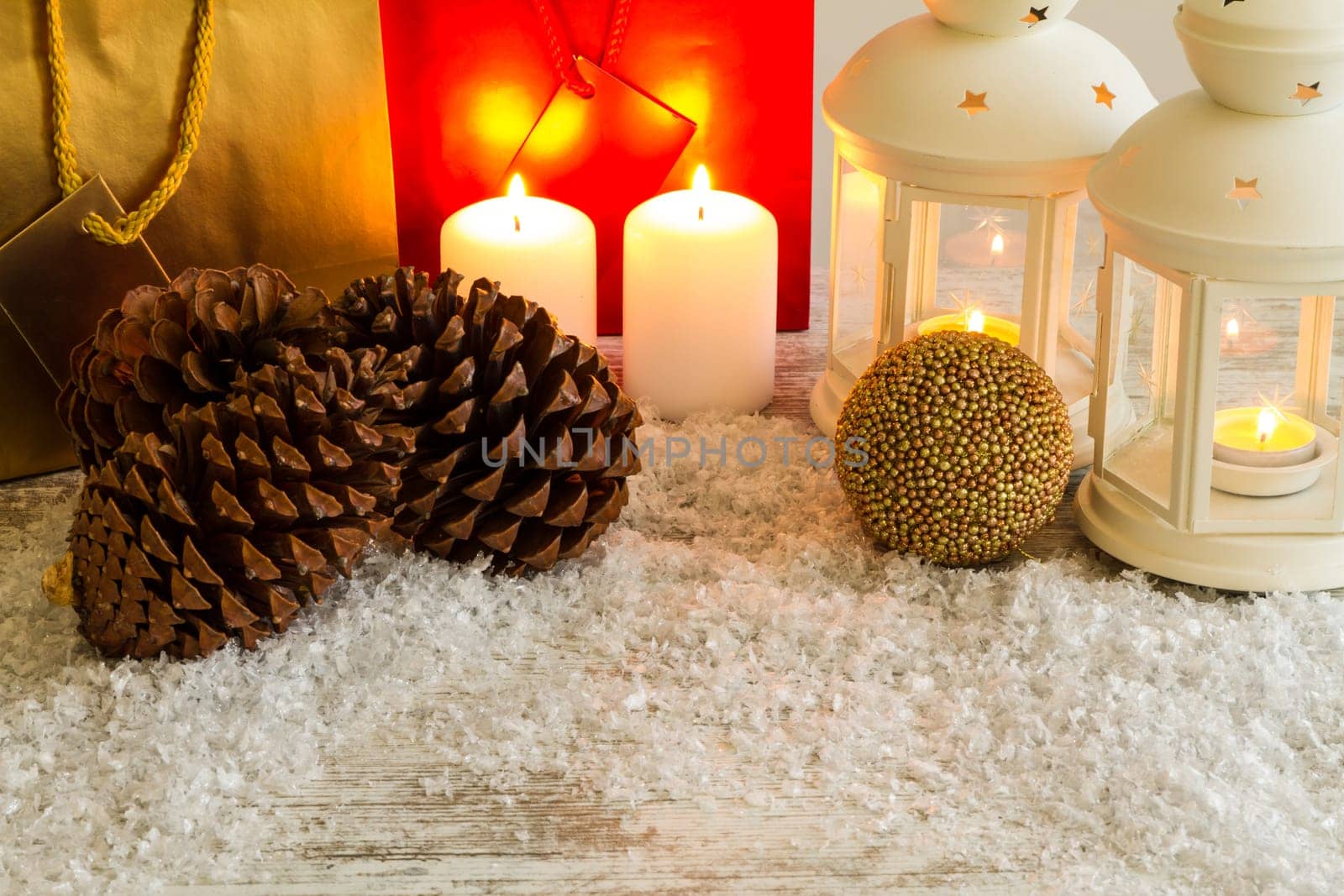 Wooden Christmas background with candles, pine cones, shopping bags and baubles..
