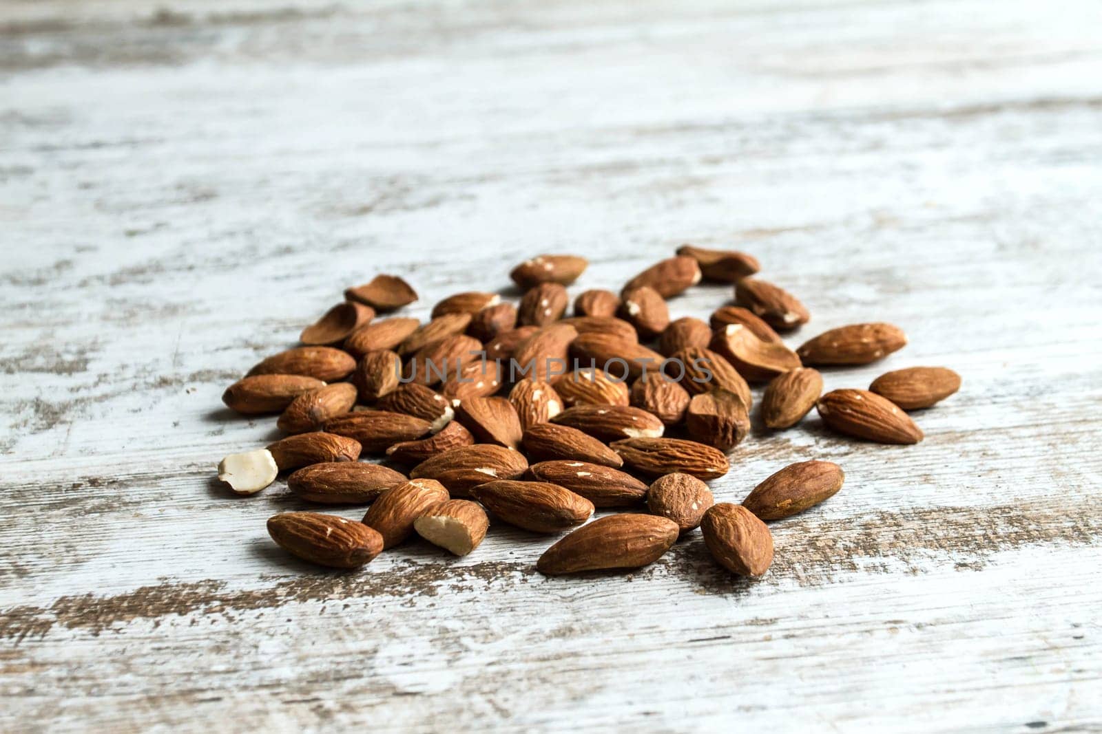 Many almonds over a wooden table, background.