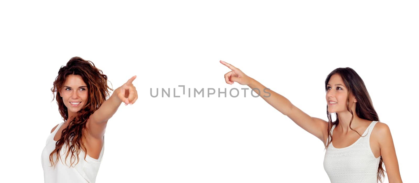 Two young pretty girls indicating something isolated on a white background