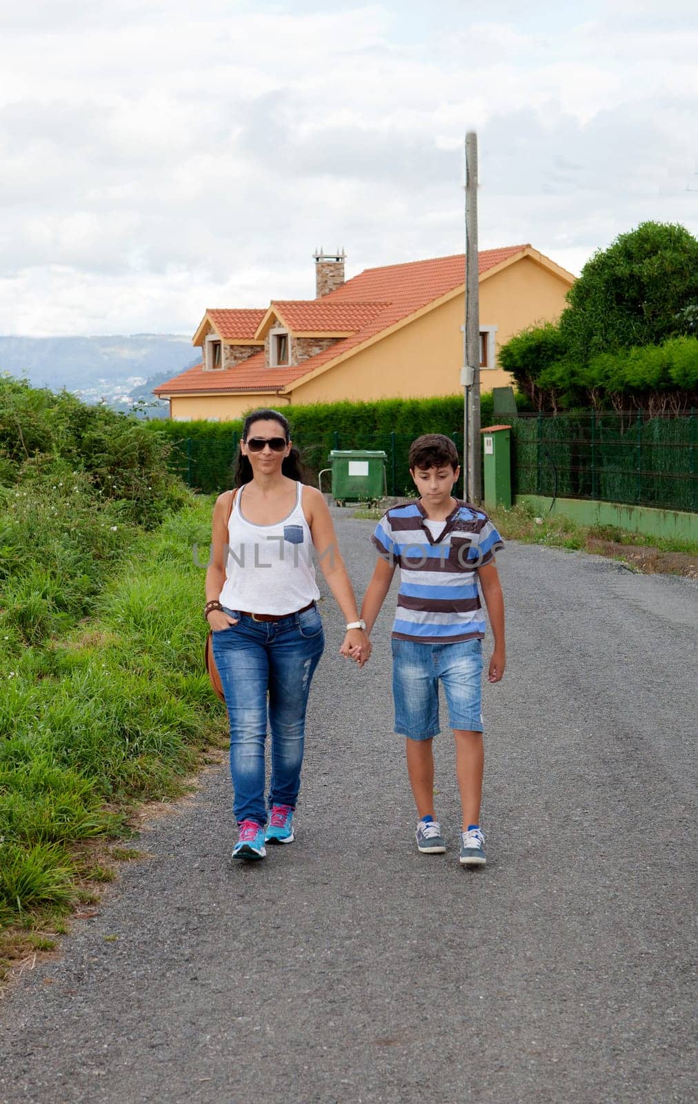 Woman with her son walking with a house background