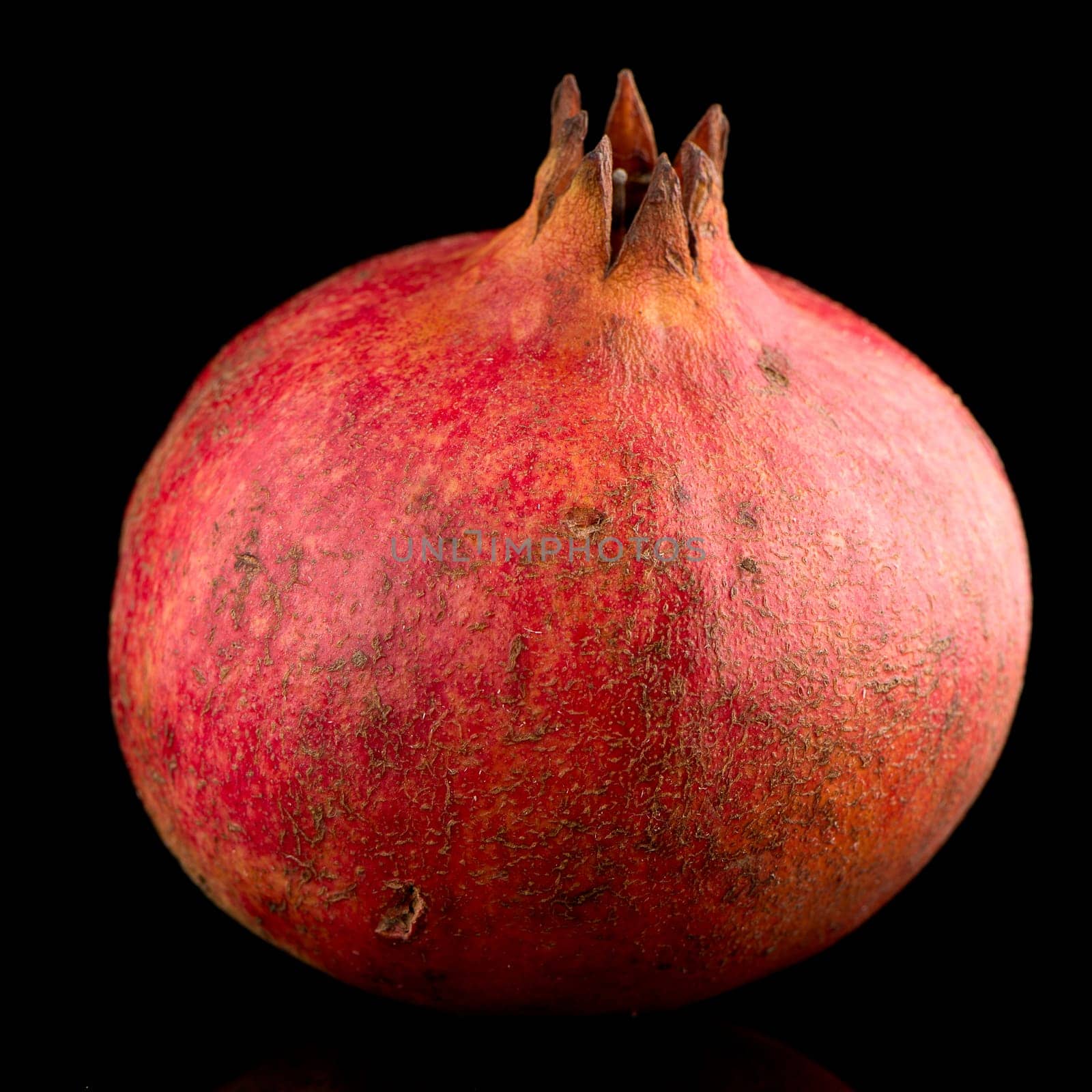 Ripe pomegranate fruit with leaves on black background