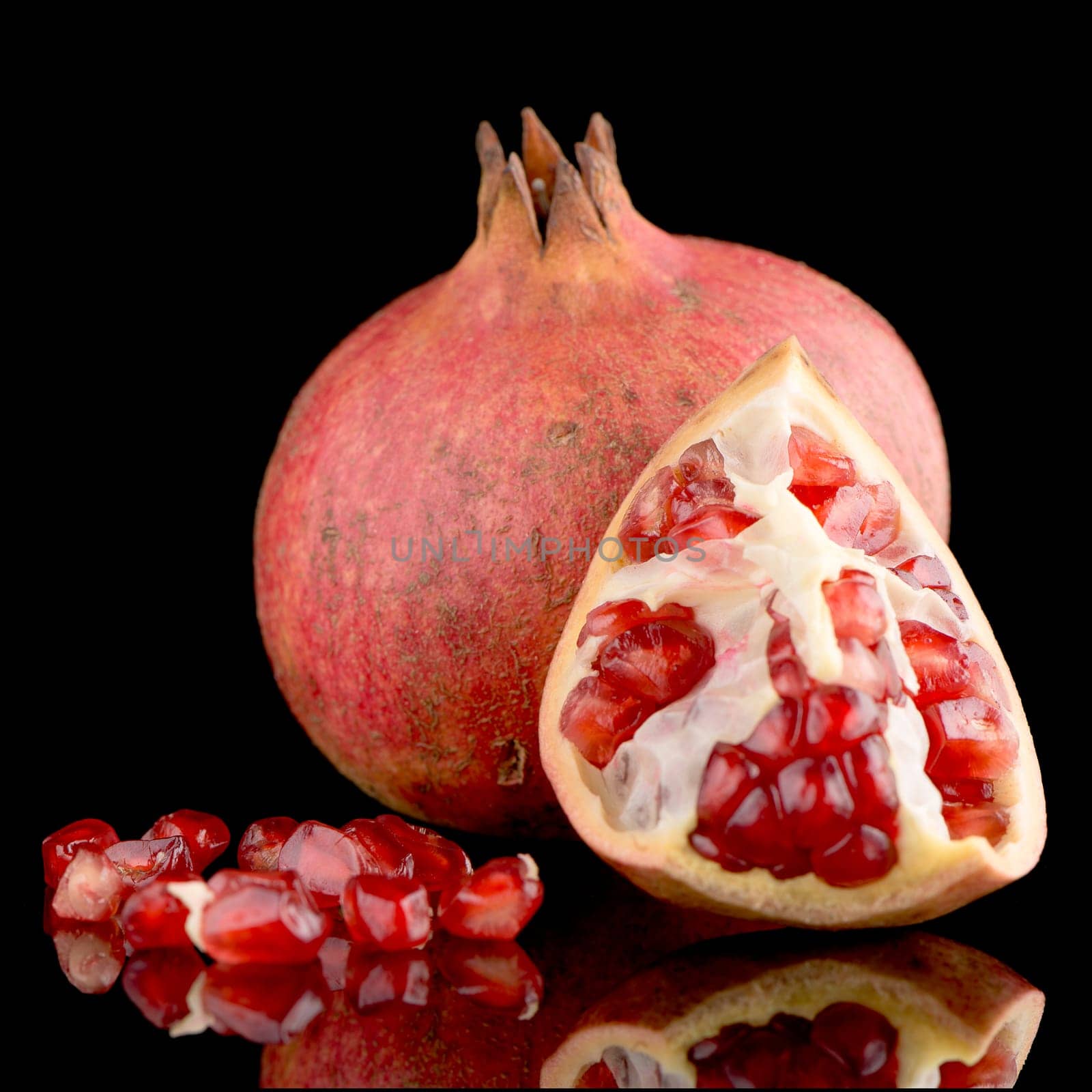 Ripe pomegranate fruit with leaves on black background