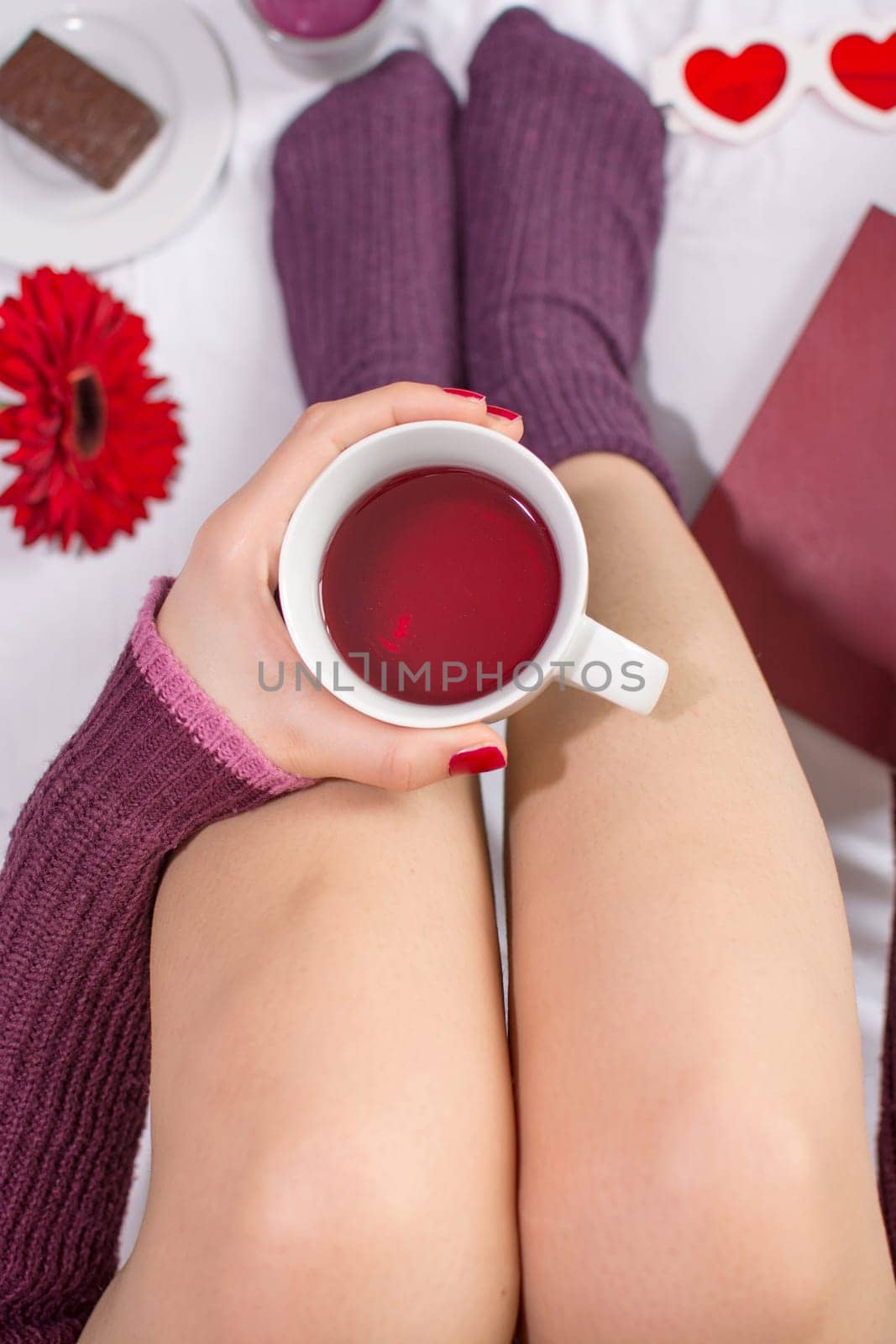 Woman having a cup of red fruit tea in bed