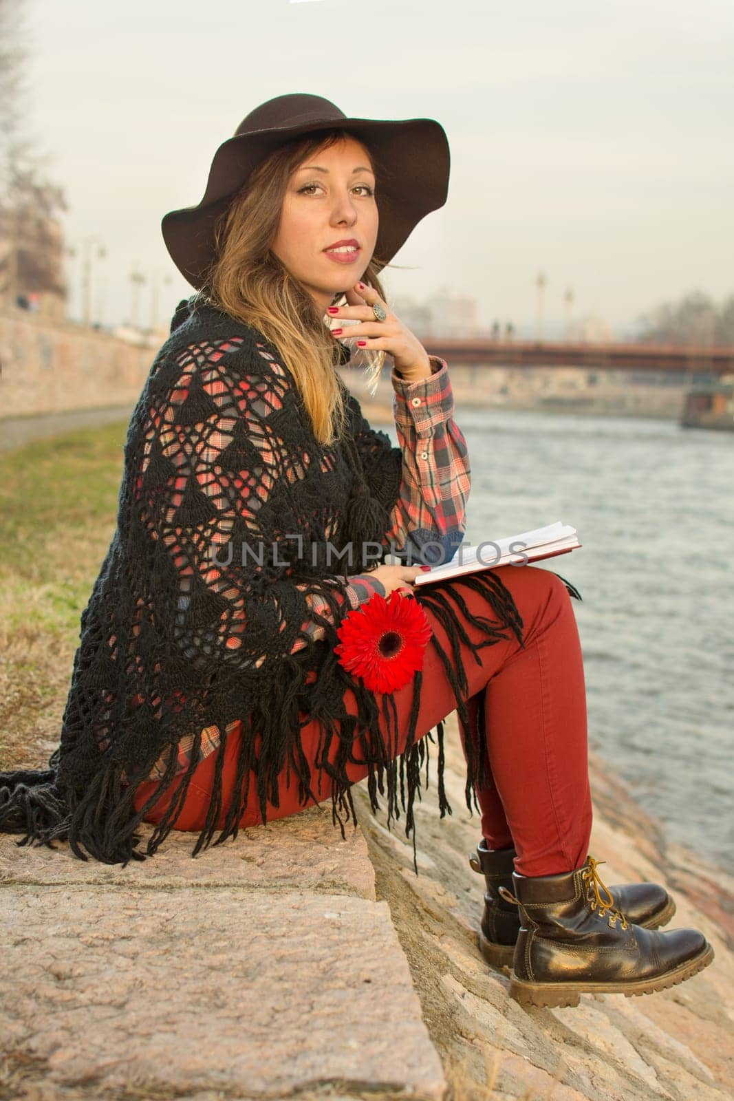 Beautiful brunette girl with a book by the river bank