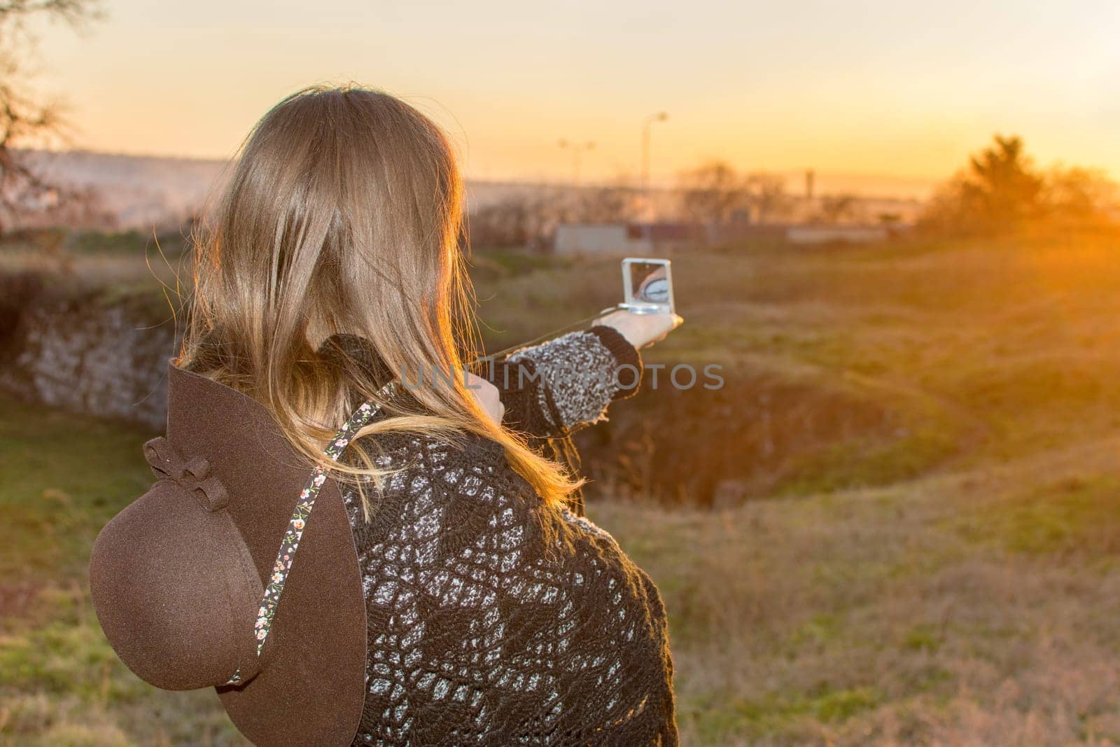 Girl pointing her compass at the sunset
