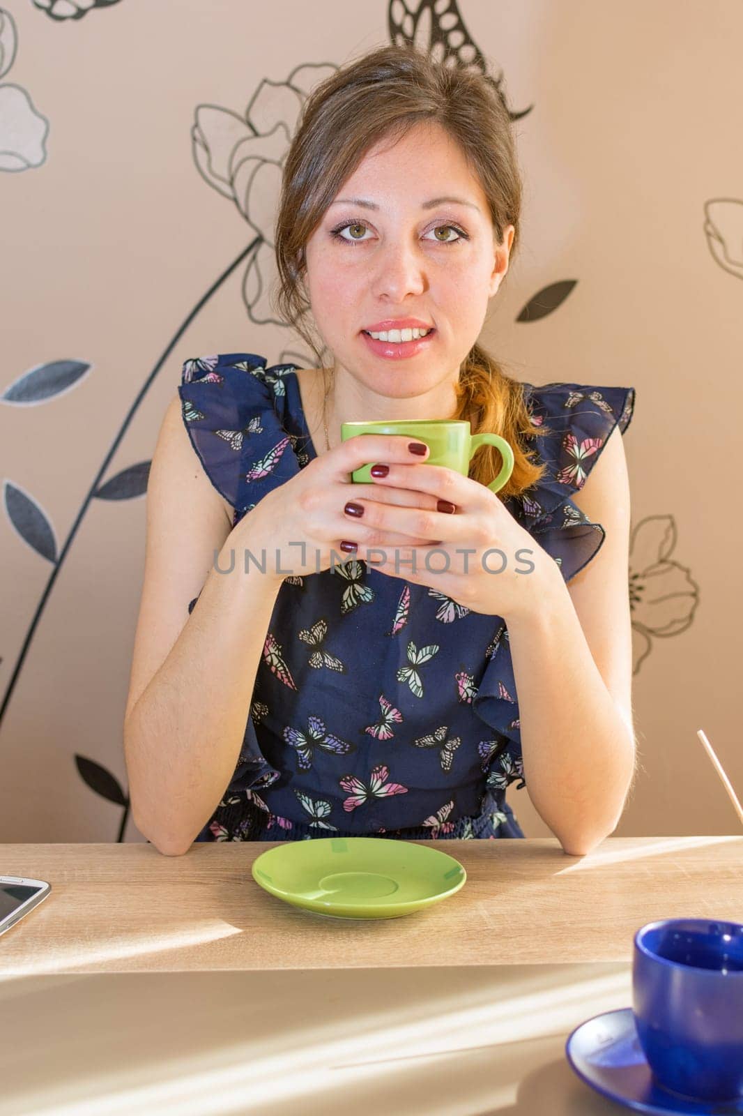 Smiling brunette drinking coffee at the kitchen table
