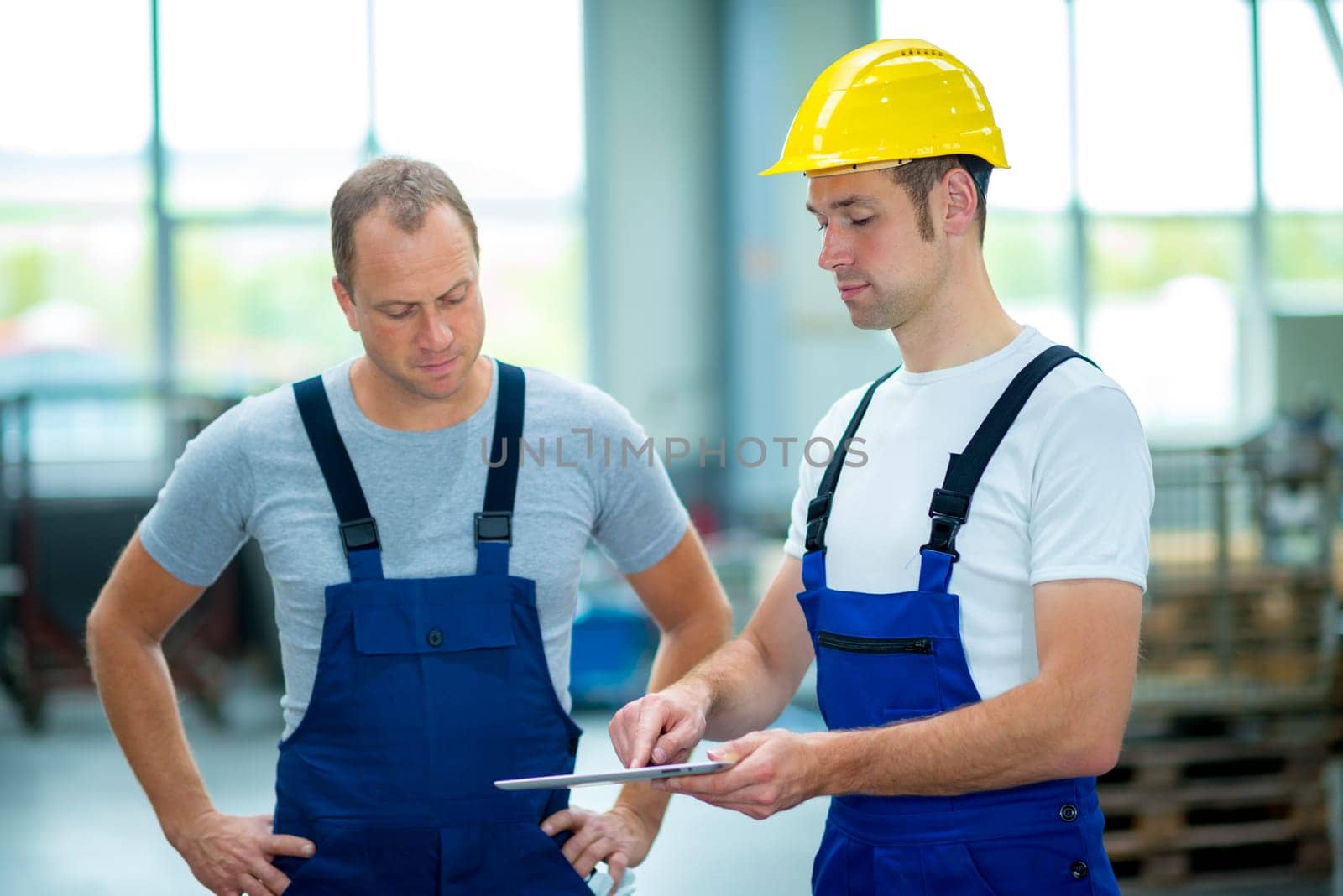 two young worker in factory using tablet pc