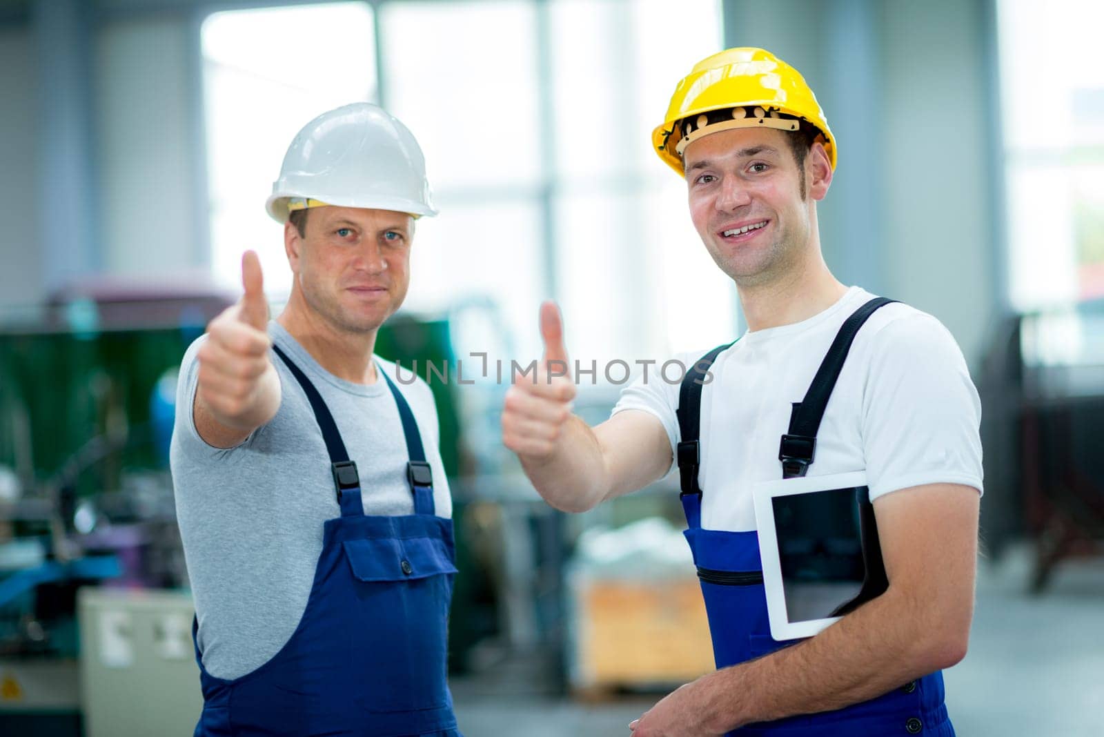 two young worker in factory with thumb up