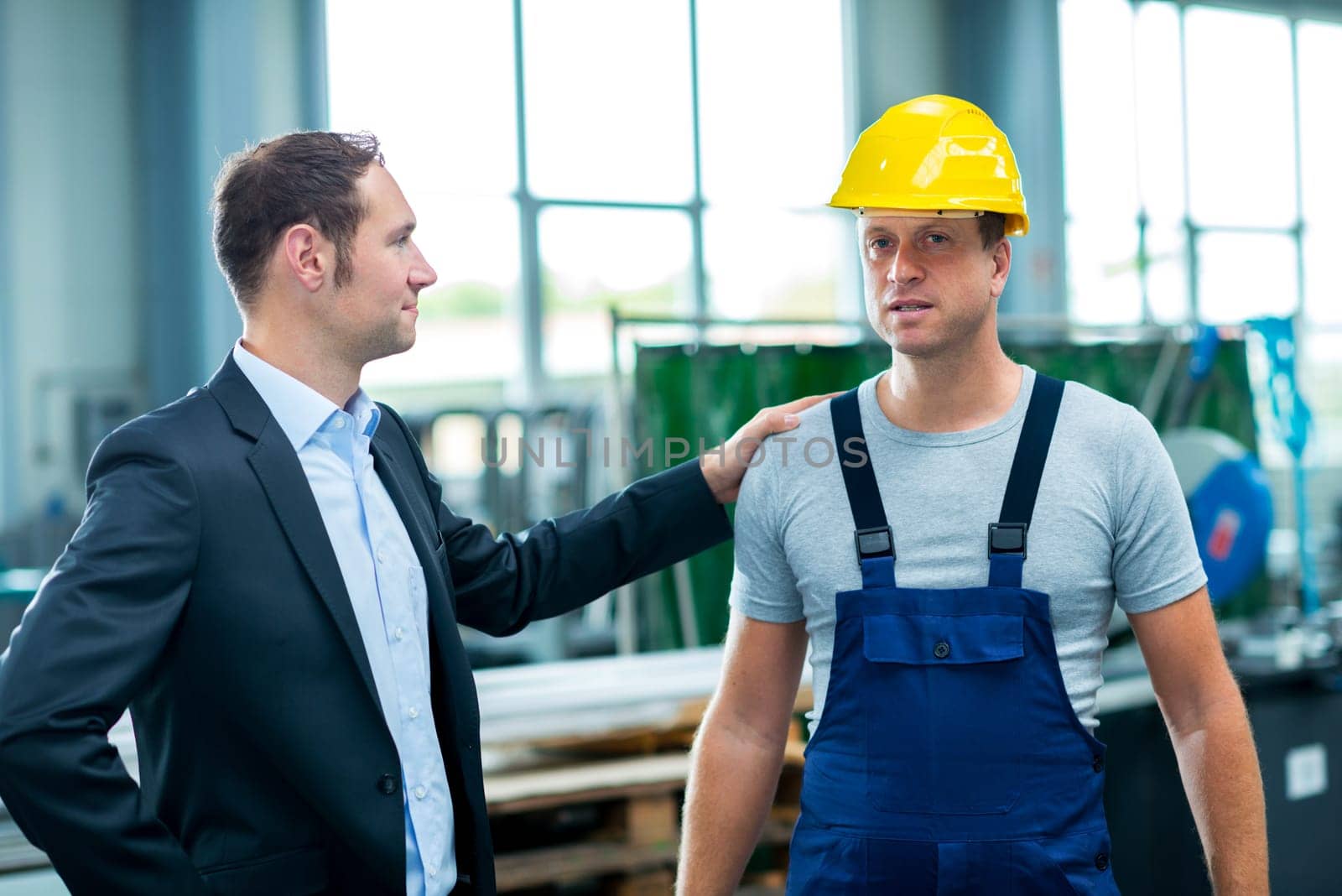 young boss with worke in the background in his factory