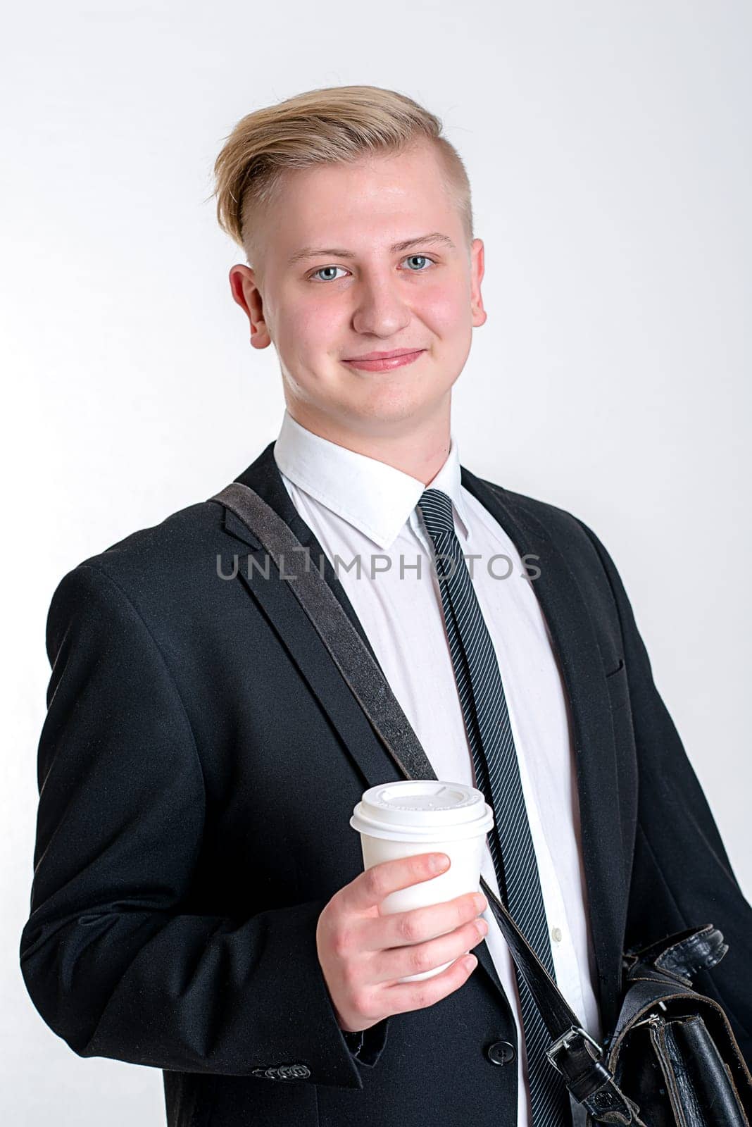 portrait of a young business man in black suit with coffee mug
