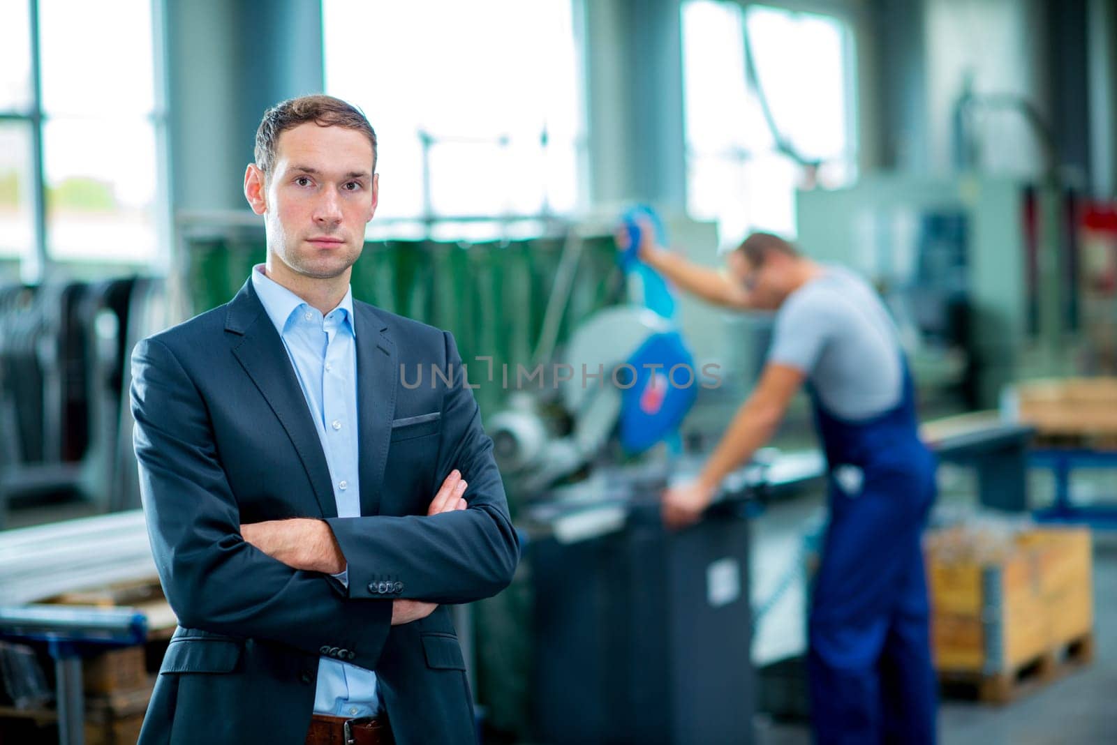 young boss with worke in the background in his factory